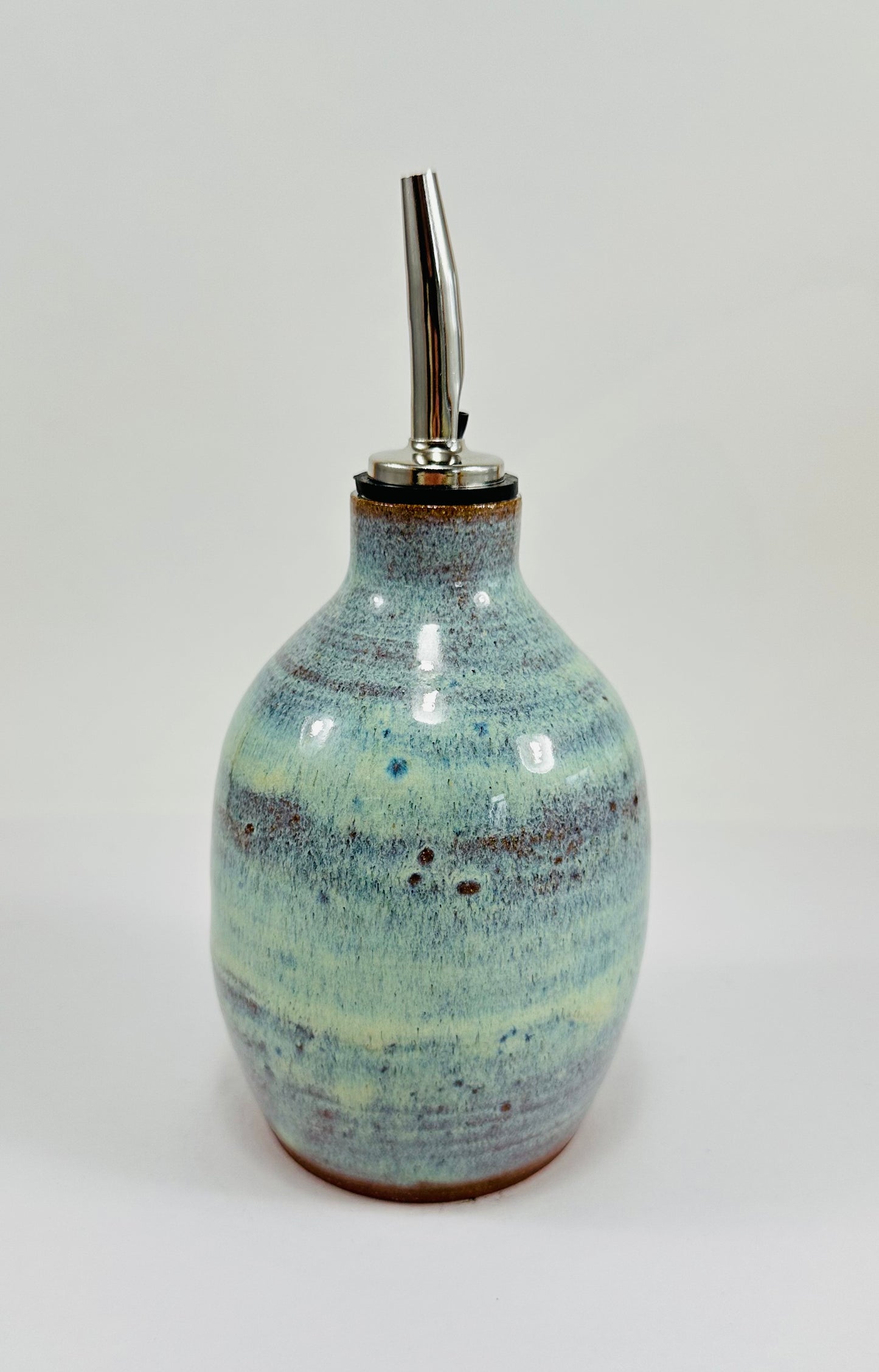 A handmade ceramic oil decanter glazed in a beautiful green and brown glaze on red clay.