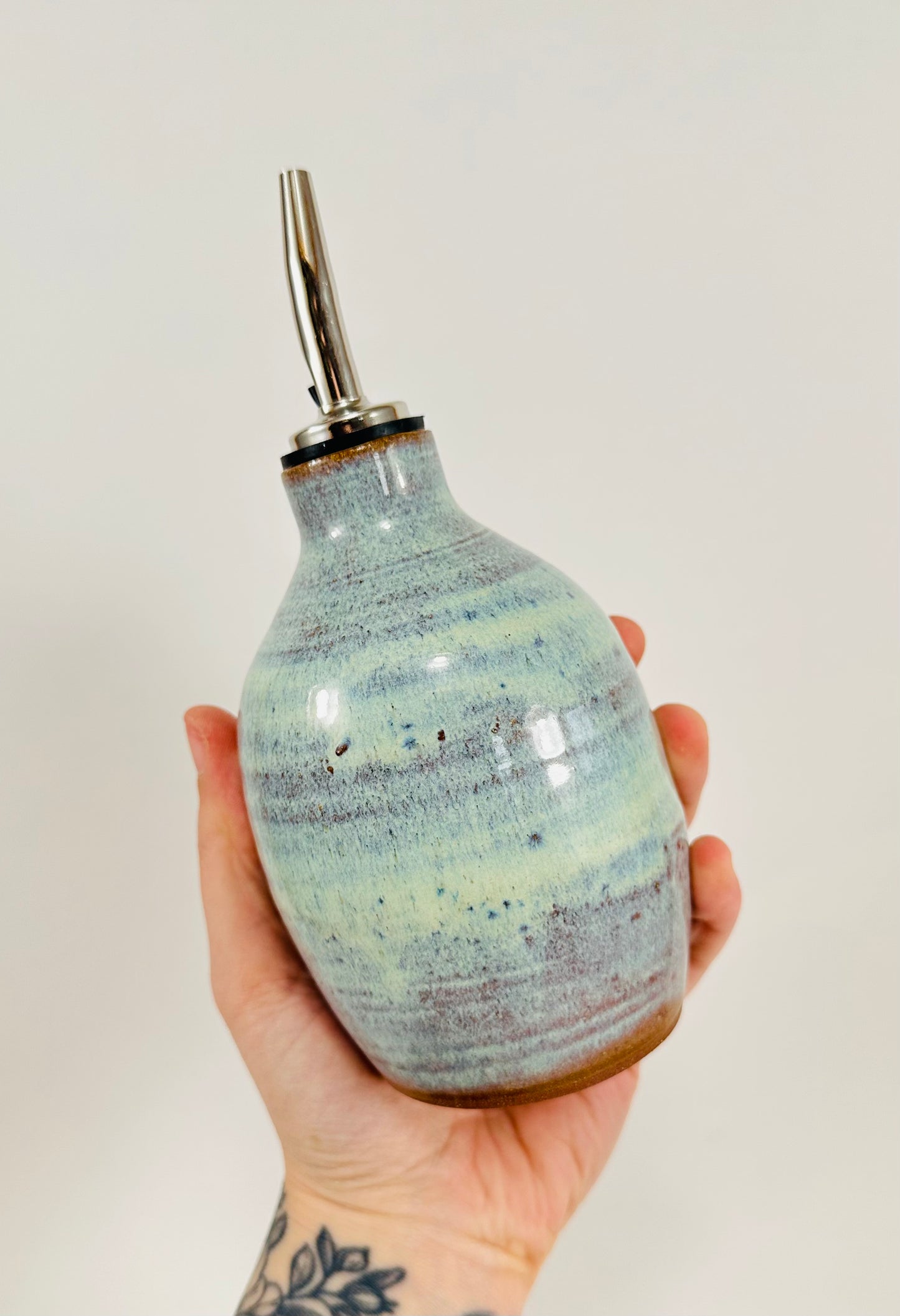 A handmade ceramic oil decanter glazed in a beautiful green and brown glaze on red clay.