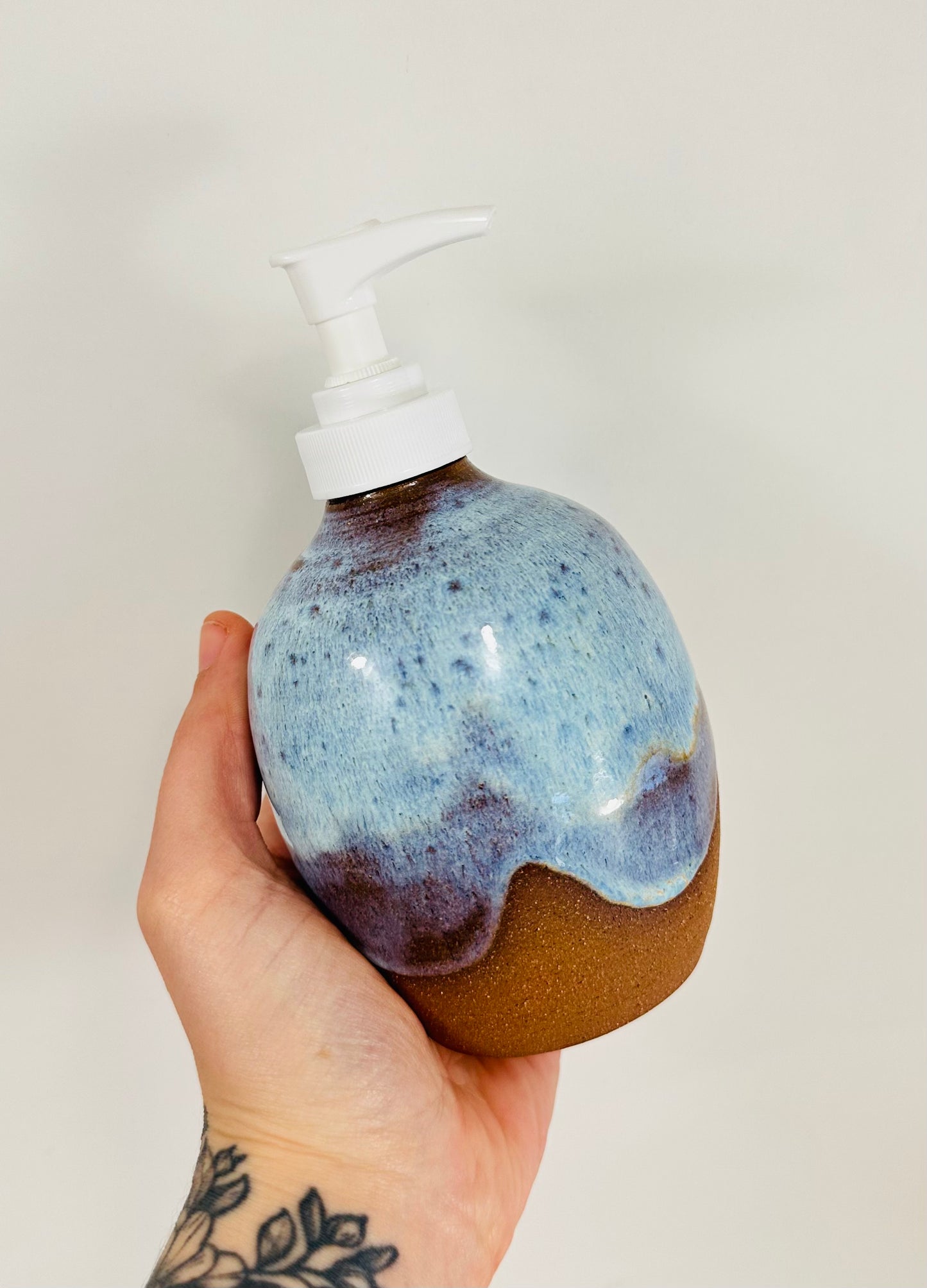 A handmade ceramic soap dispenser in red clay with a beautiful blue glaze.