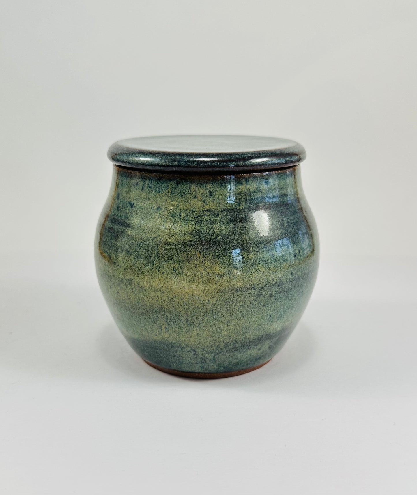 A handmade ceramic jar in red clay with a beautiful green glaze.