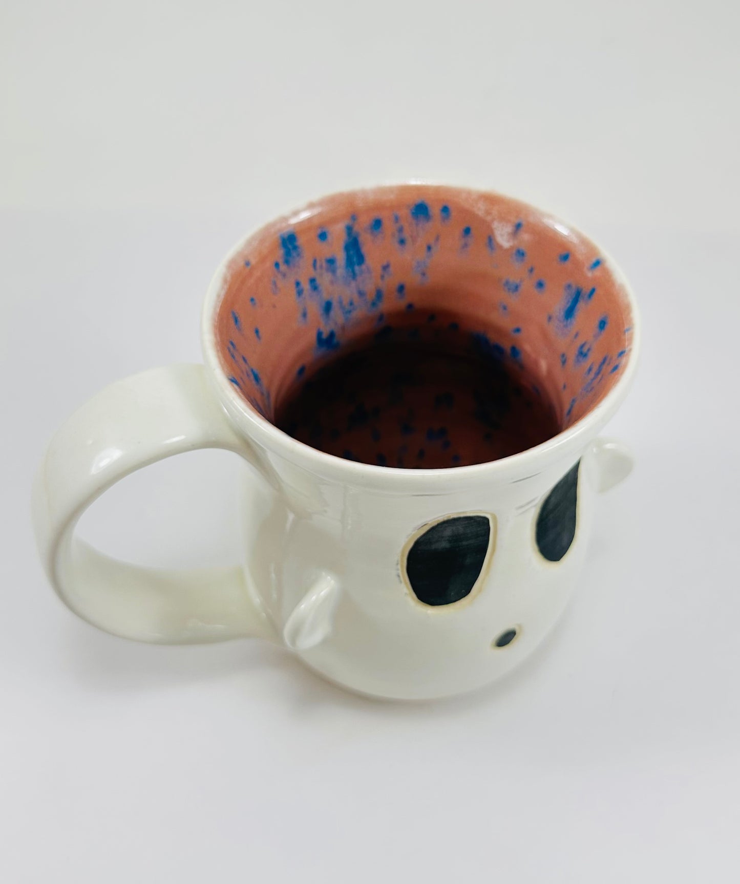 Handmade ceramic ghost mug with white glaze on the outside and purple on the inside.