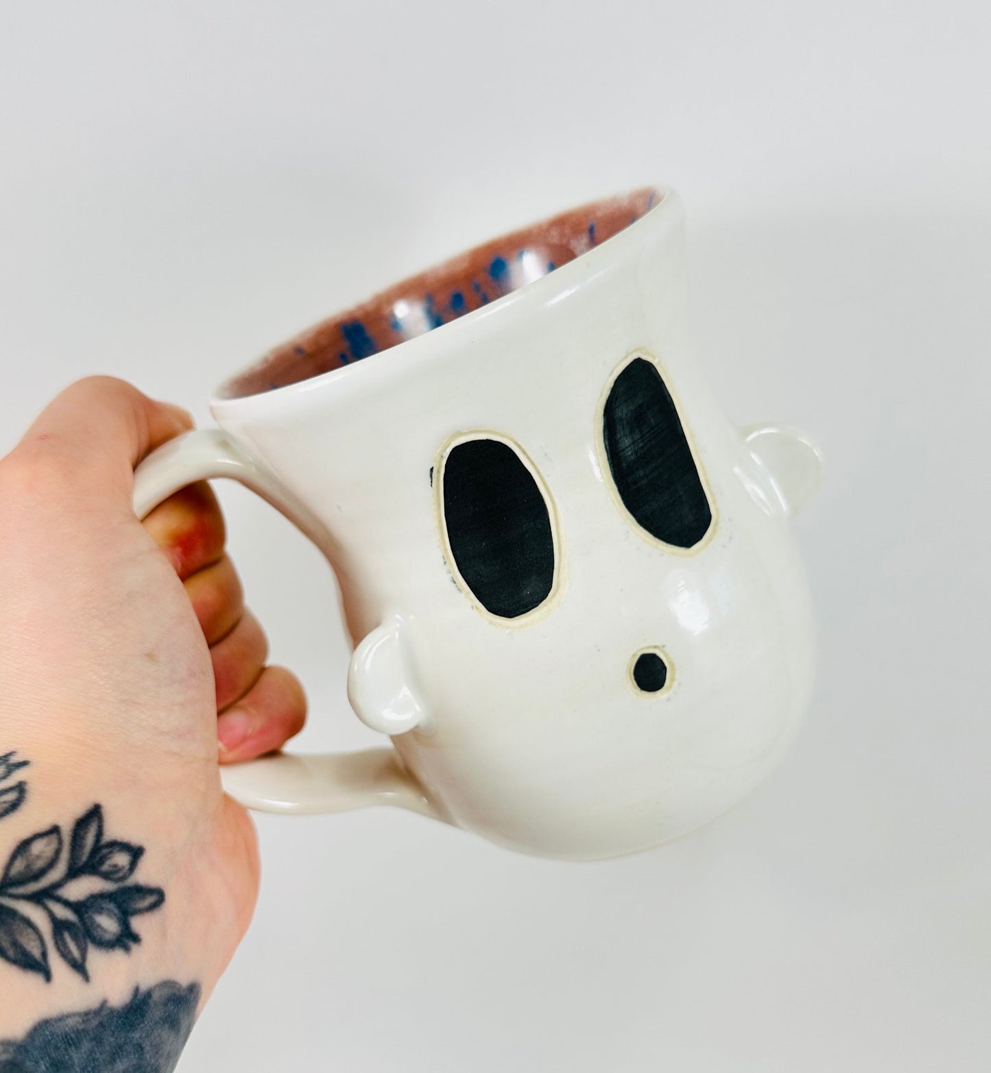 Handmade ceramic ghost mug with white glaze on the outside and purple on the inside.