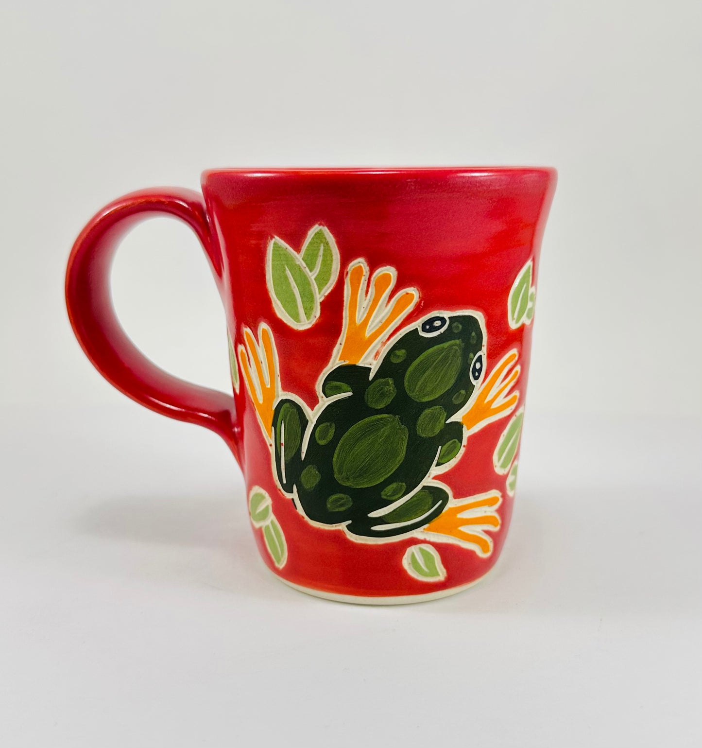 Pink mug with a green frog design on a white background