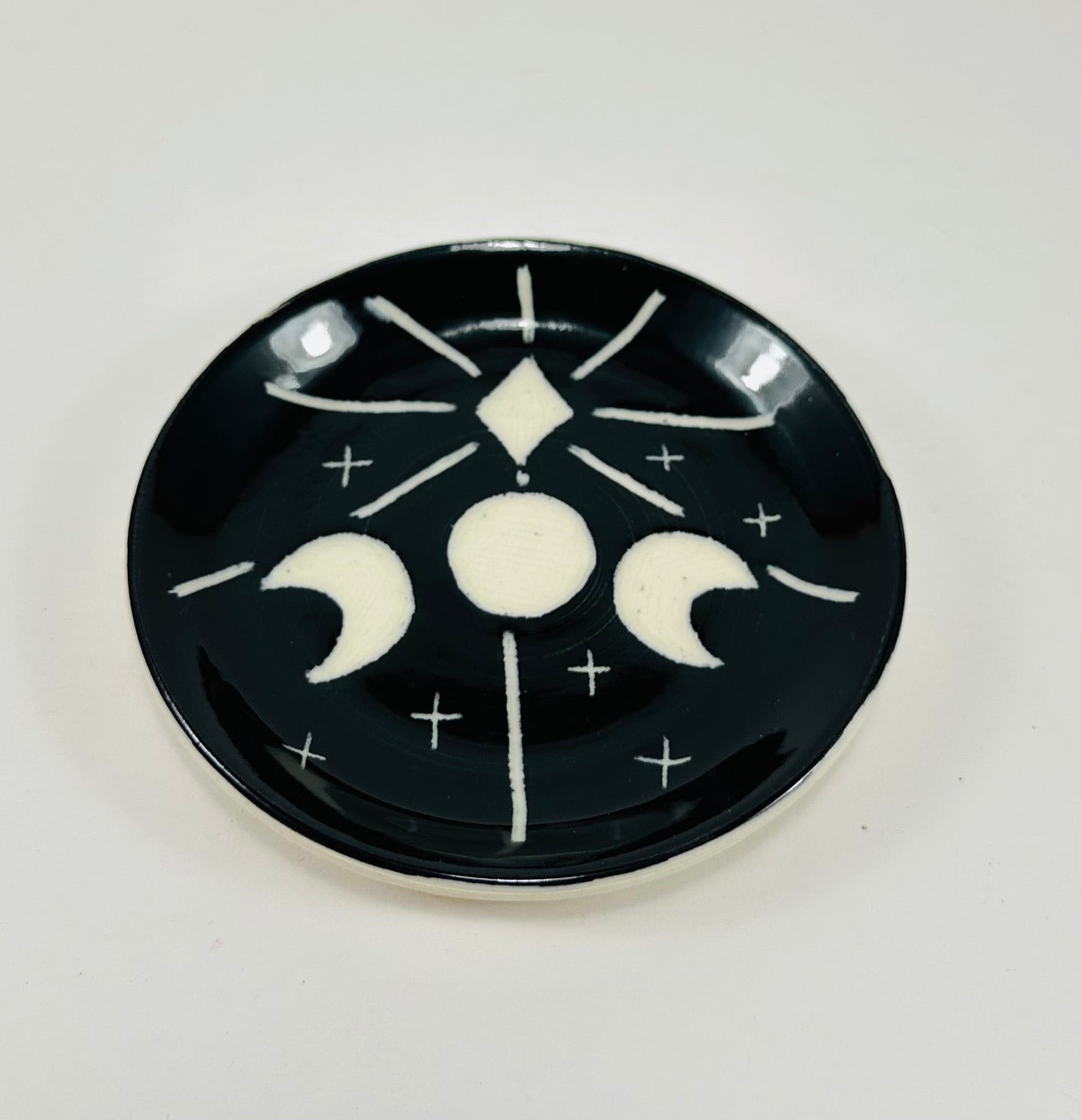 Handmade trinket dish in black and white glaze with moons and stars.