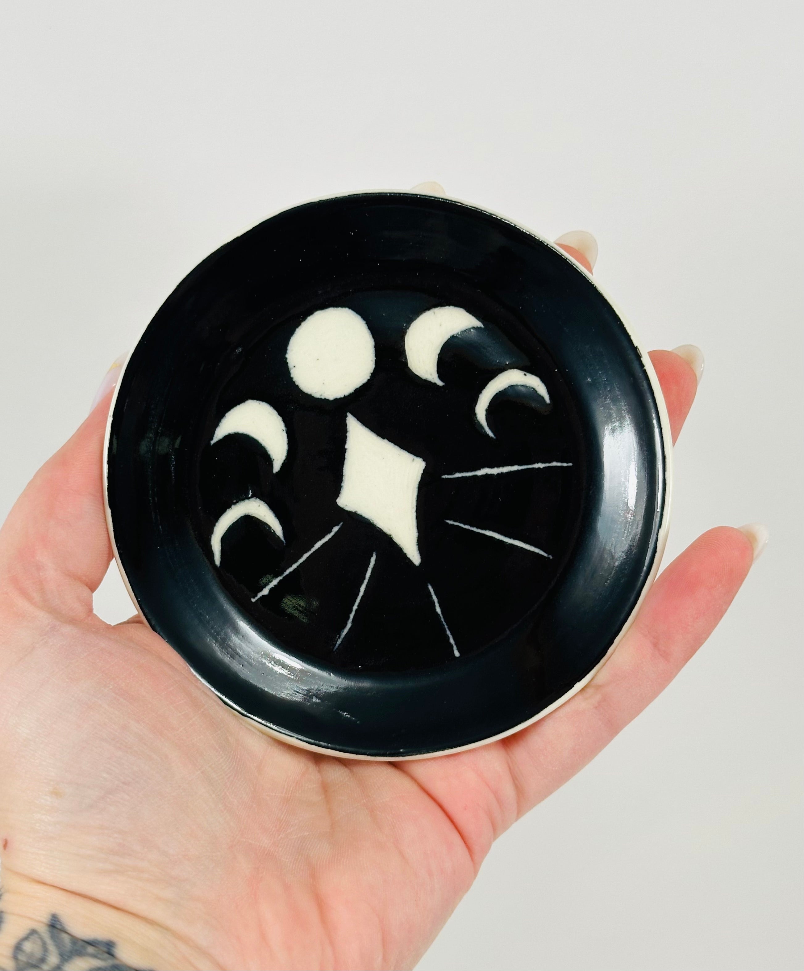 Handmade trinket dish in black and white glaze with moons and stars.