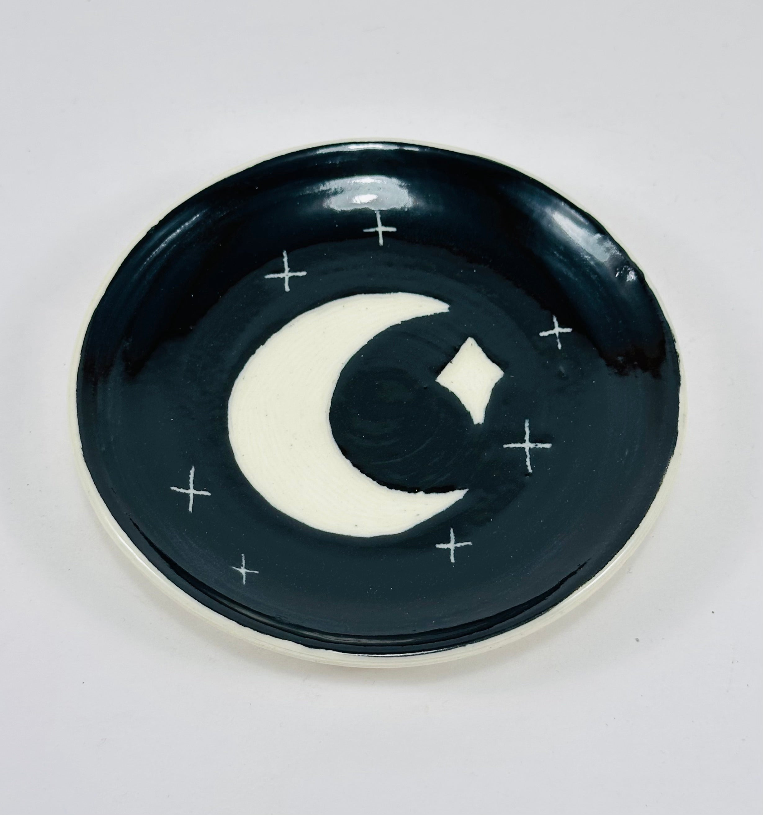 Handmade trinket dish in black and white glaze with moons and stars.