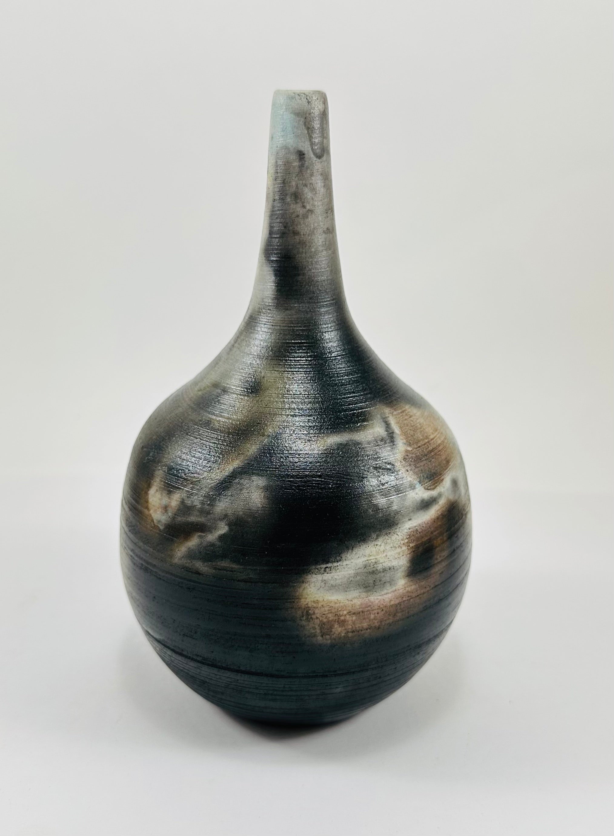 Handmade, skinny neck vase with a brown, white, black and yellow smokey finish.