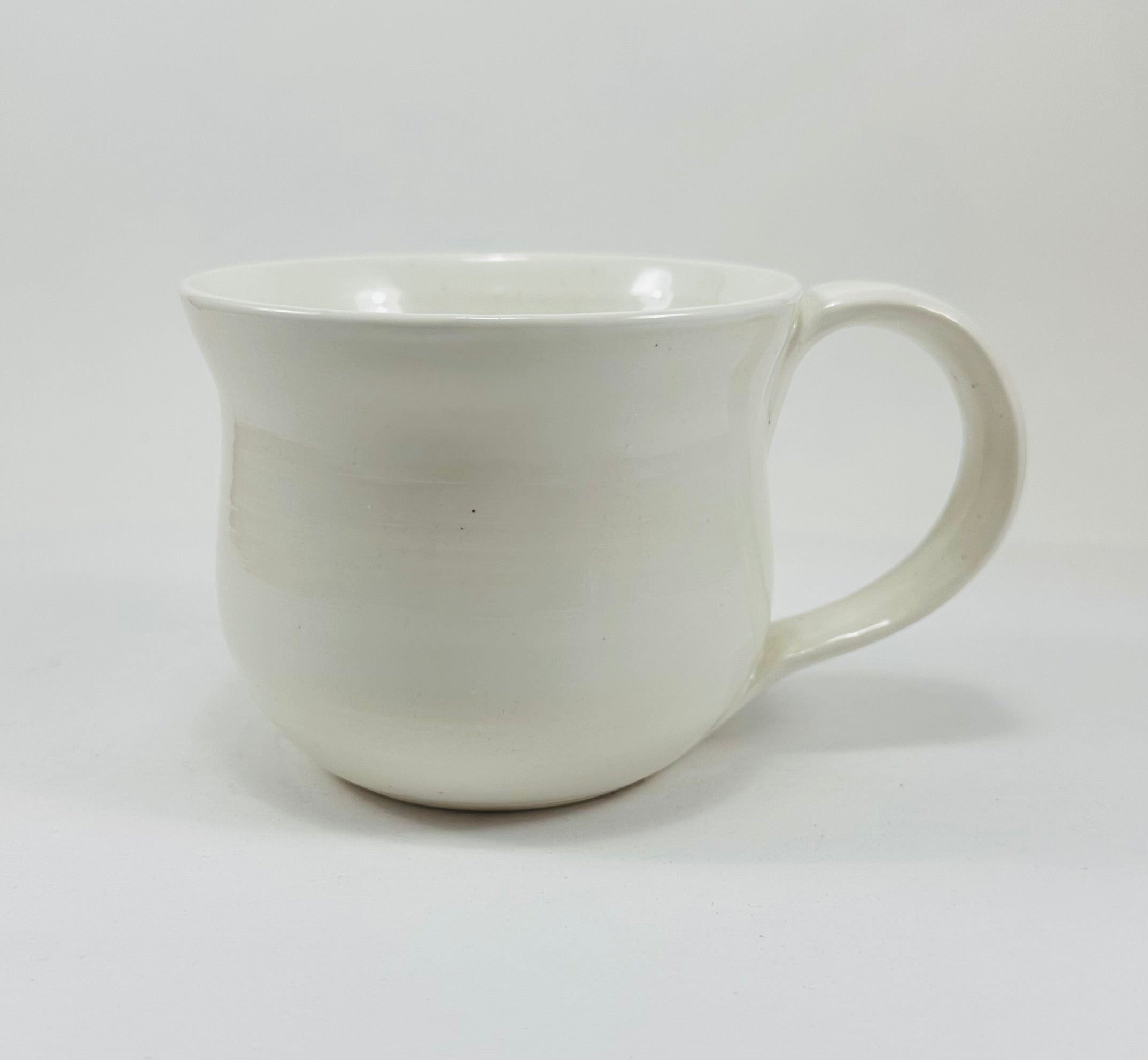A handmade ceramic mug in a beautiful white glaze with a cicada illustration on it.