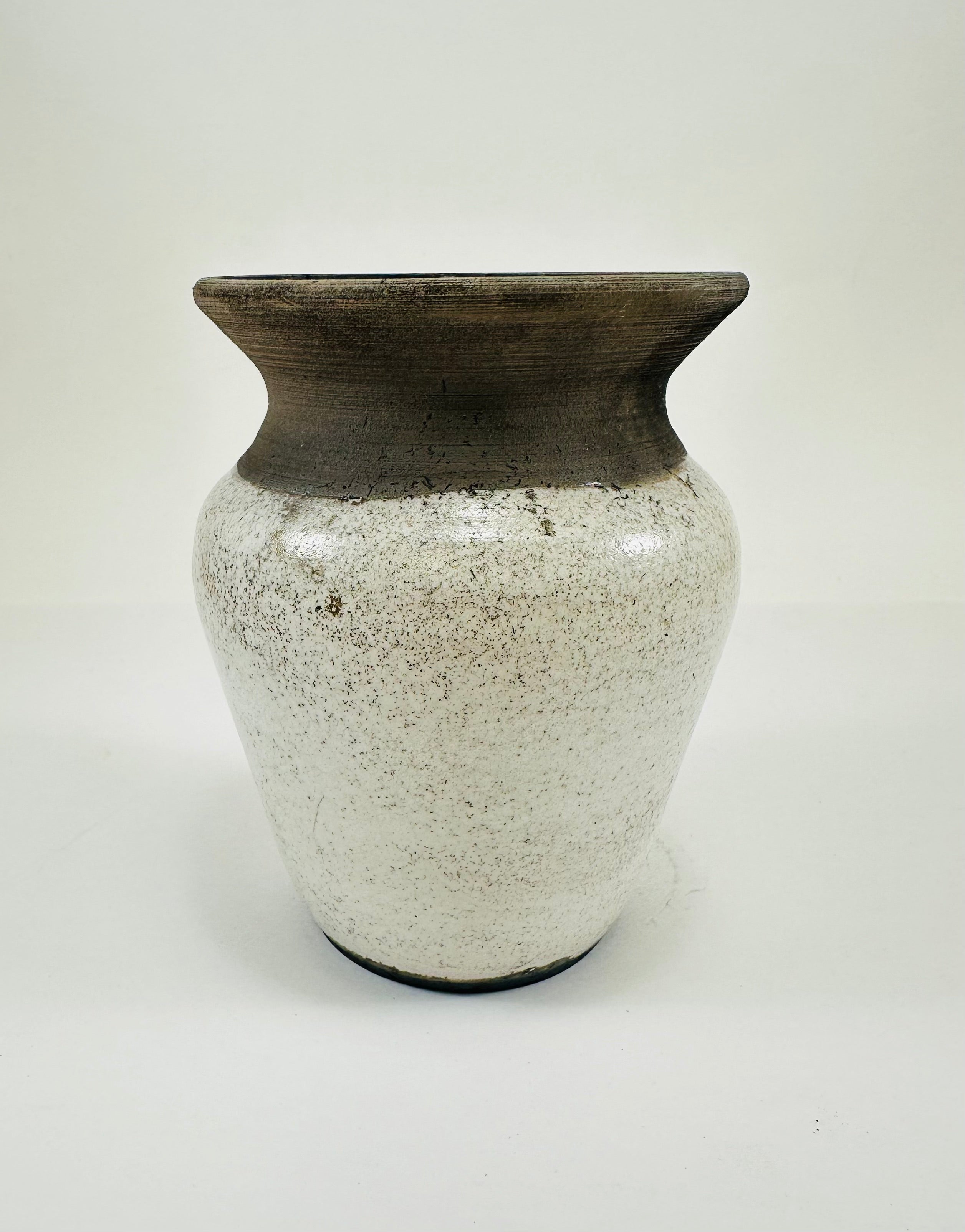 A hand made ceramic vase with a stunning, matte Raku glaze. The colours show whites and blacks. The vase has a V shaped body, narrow neck and wide opening. The top third of the pot is black and the bottom two thirds is white.