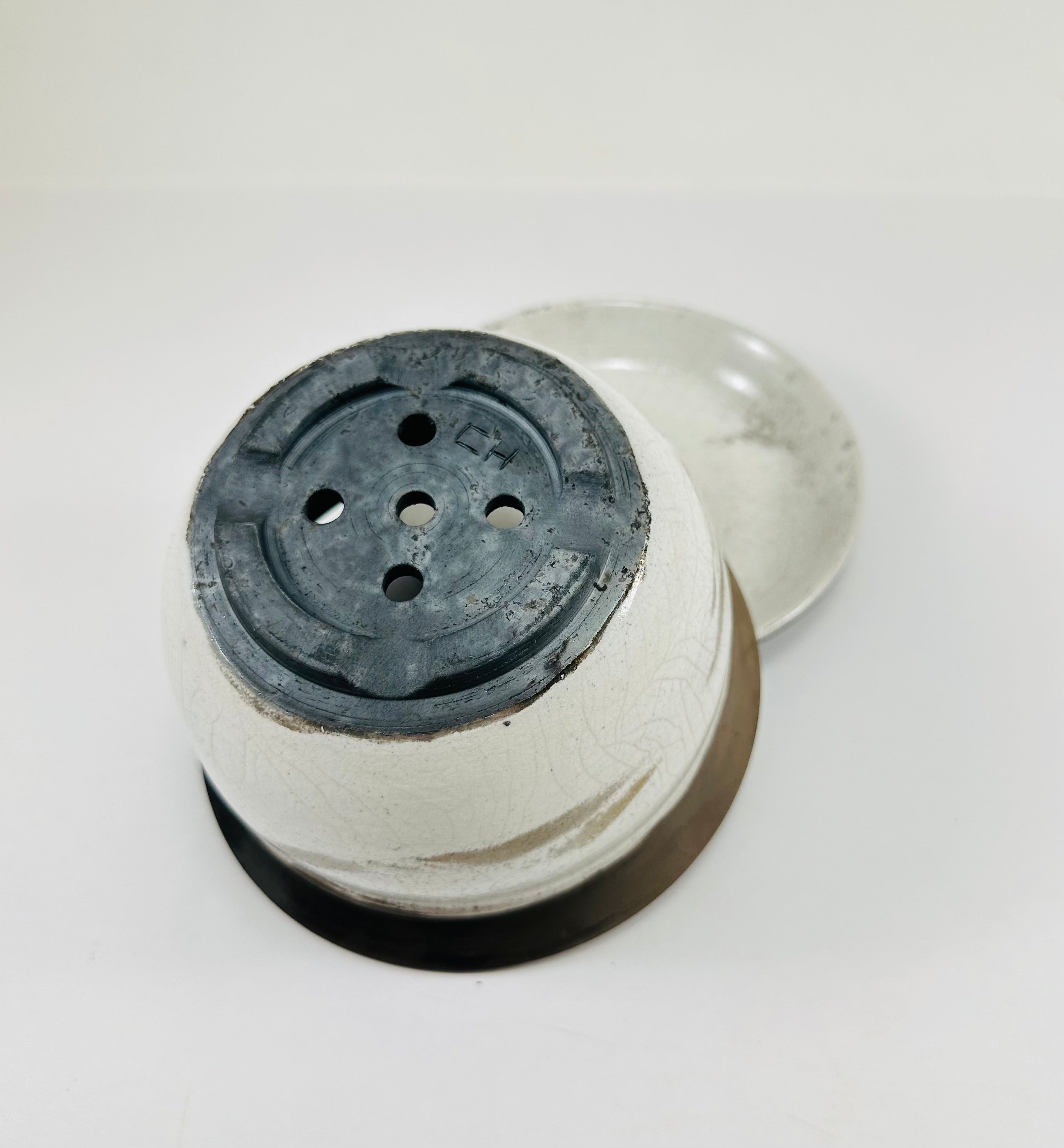 A hand made ceramic planter and plate with a stunning, matte Raku glaze. The colours show whites and blacks. The planter is bowl shaped and has a flared opening. The top rim of the planter is black and the bottom body and plate is white.