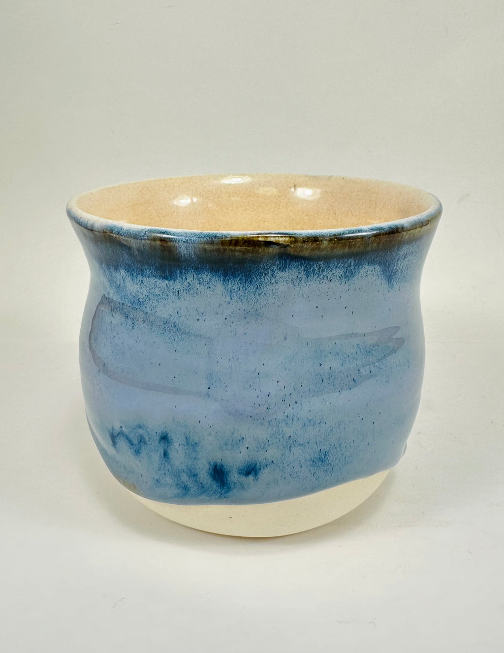 A handmade ceramic planter. The planter is glazed in a beautiful blue and cream colour. The planter is round in shape with a wide flared rim. The planter is left unglazed on the inside and on the bottom quarter of the pot.
