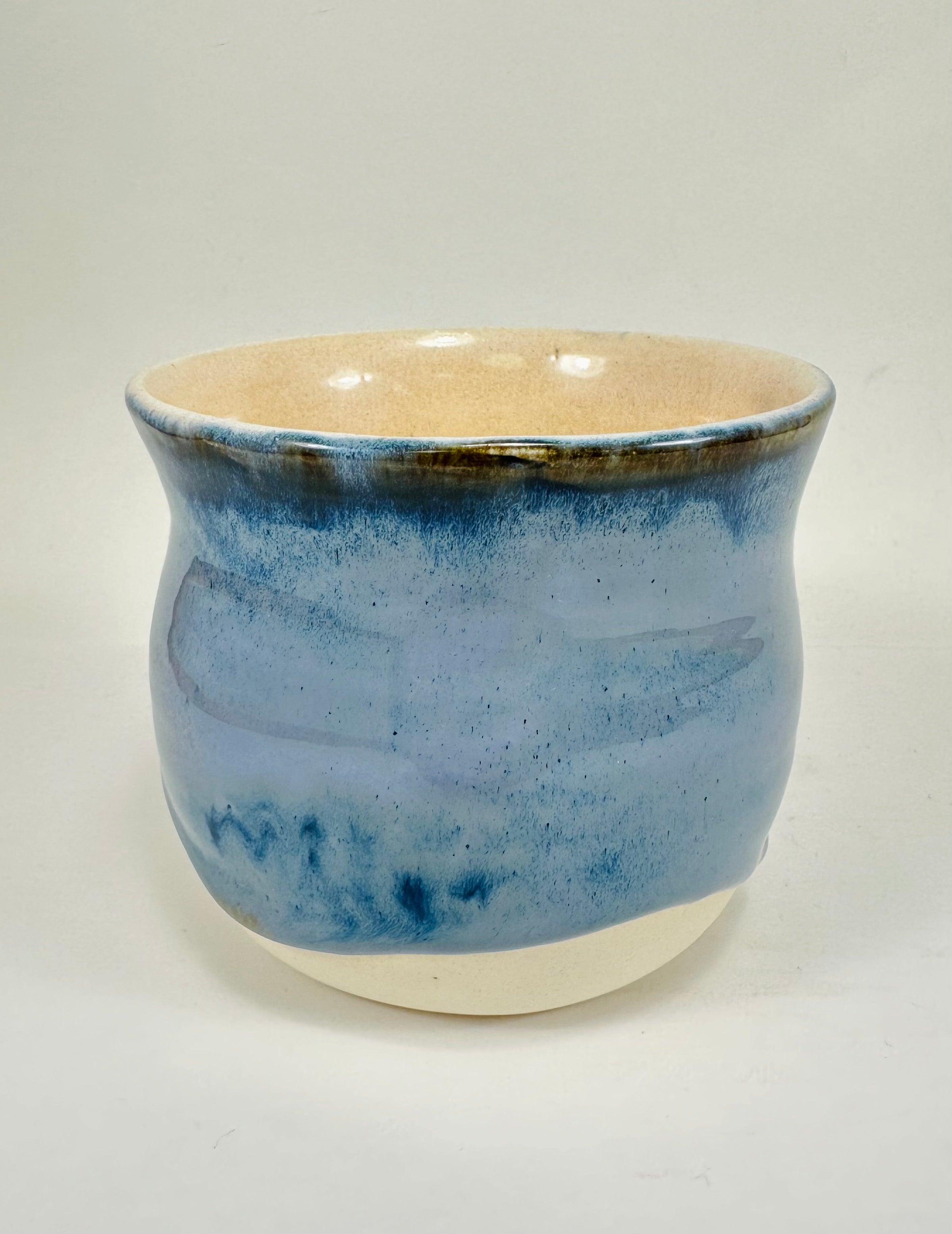 A handmade ceramic planter. The planter is glazed in a beautiful blue and cream colour. The planter is round in shape with a wide flared rim. The planter is left unglazed on the inside and on the bottom quarter of the pot.