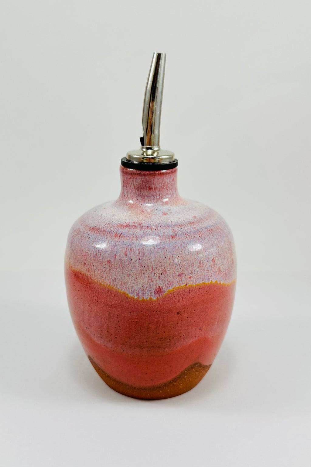 A handmade ceramic oil decanter glazed in a beautiful pink on red clay.