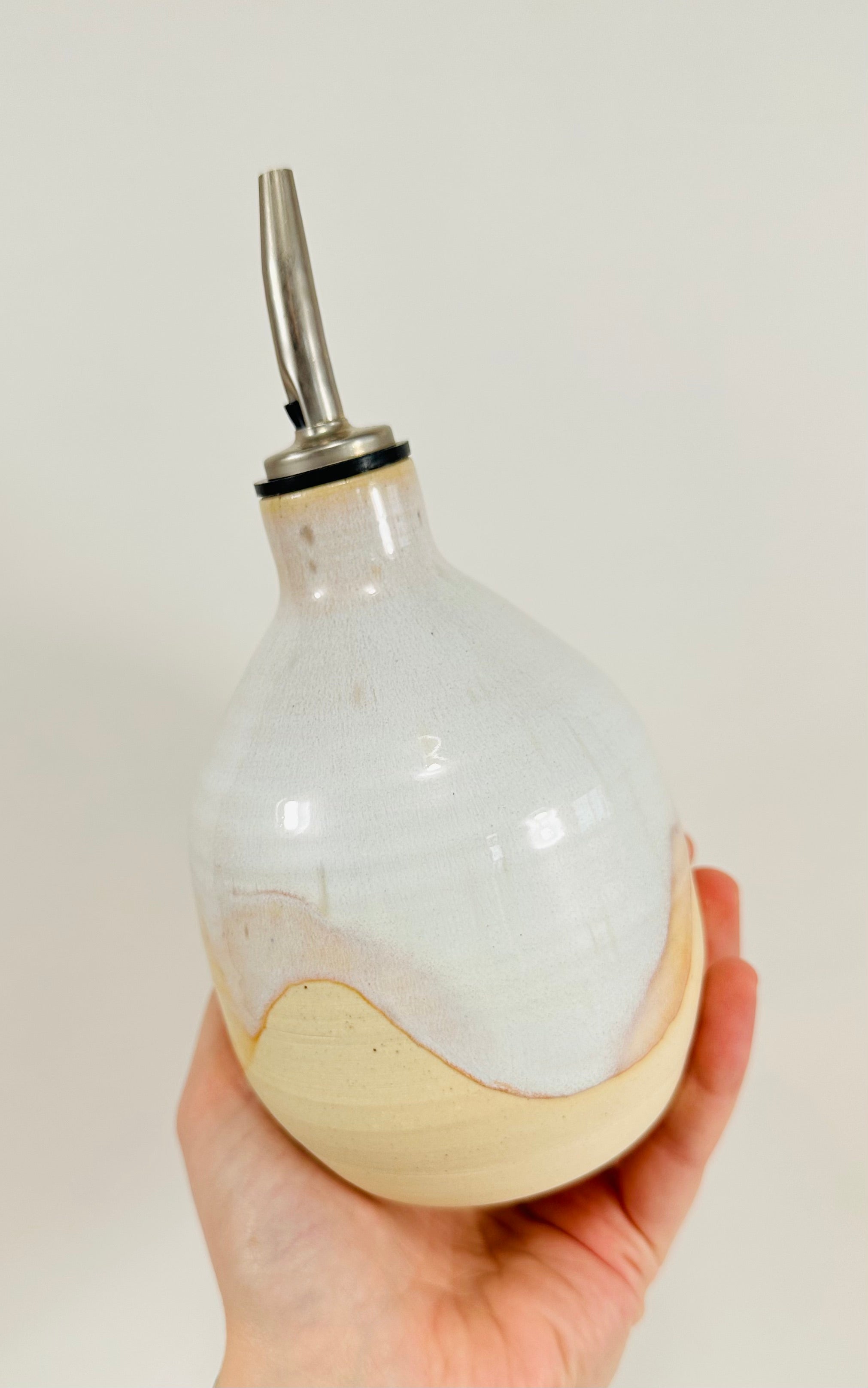 A handmade ceramic oil decanter glazed in a beautiful cream and brown on red clay.