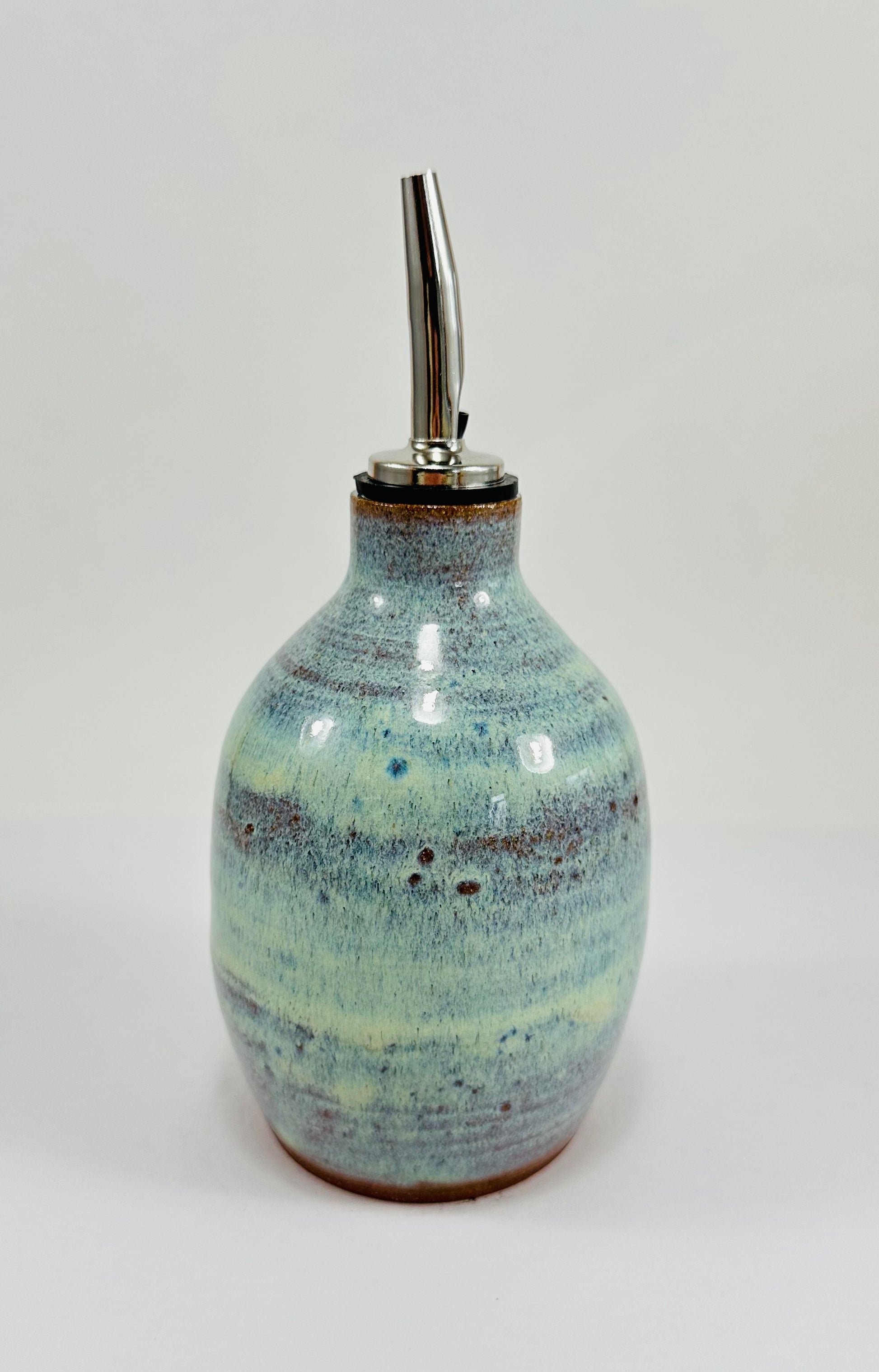 A handmade ceramic oil decanter glazed in a beautiful green and brown glaze on red clay.