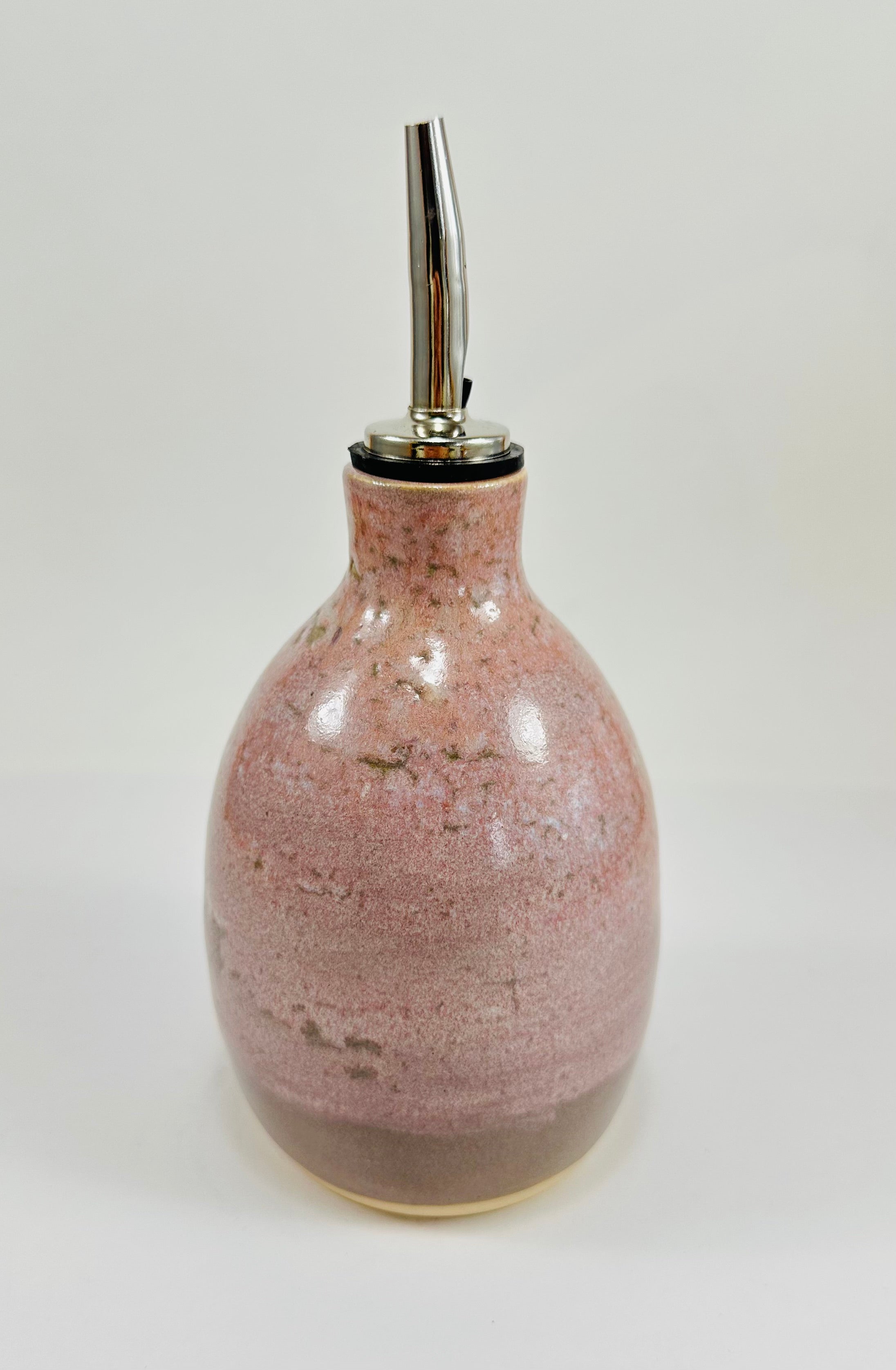 A handmade ceramic oil decanter glazed in a soft pink on porcelain clay.