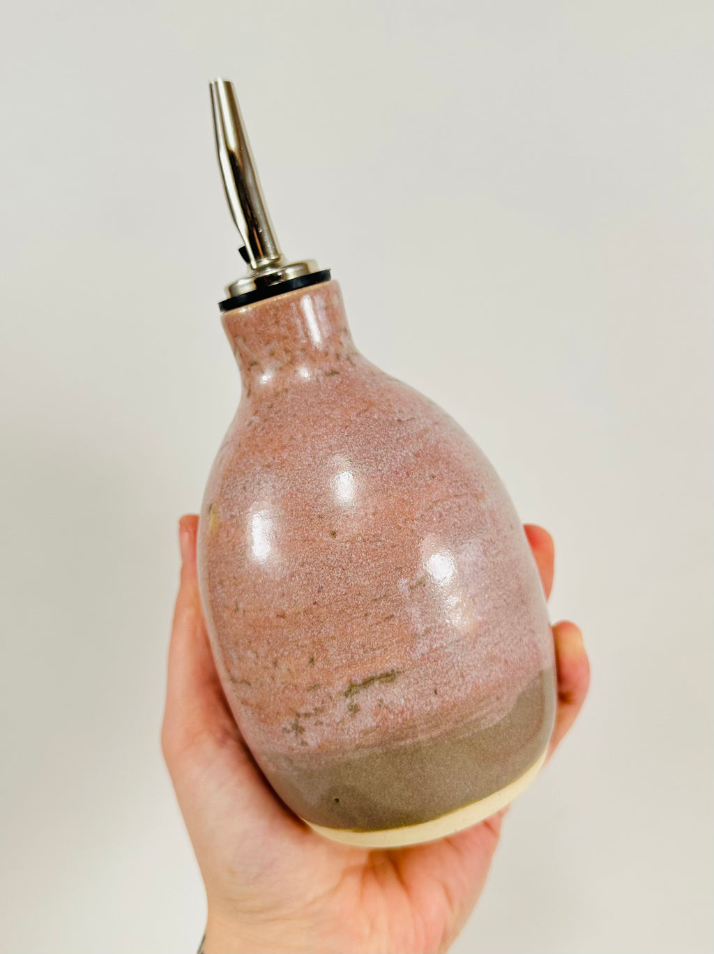 A handmade ceramic oil decanter glazed in a soft pink on porcelain clay.