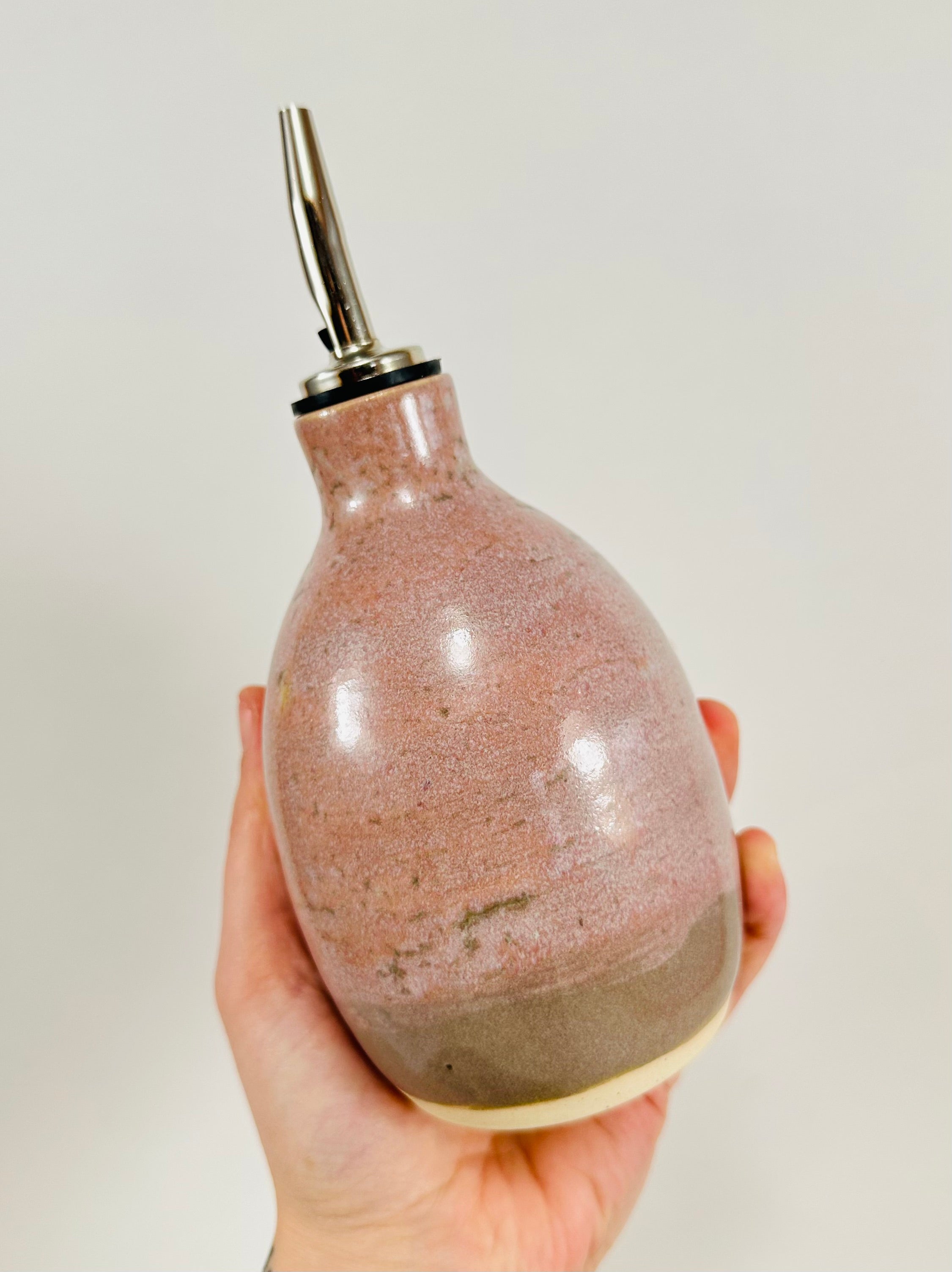 A handmade ceramic oil decanter glazed in a soft pink on porcelain clay.