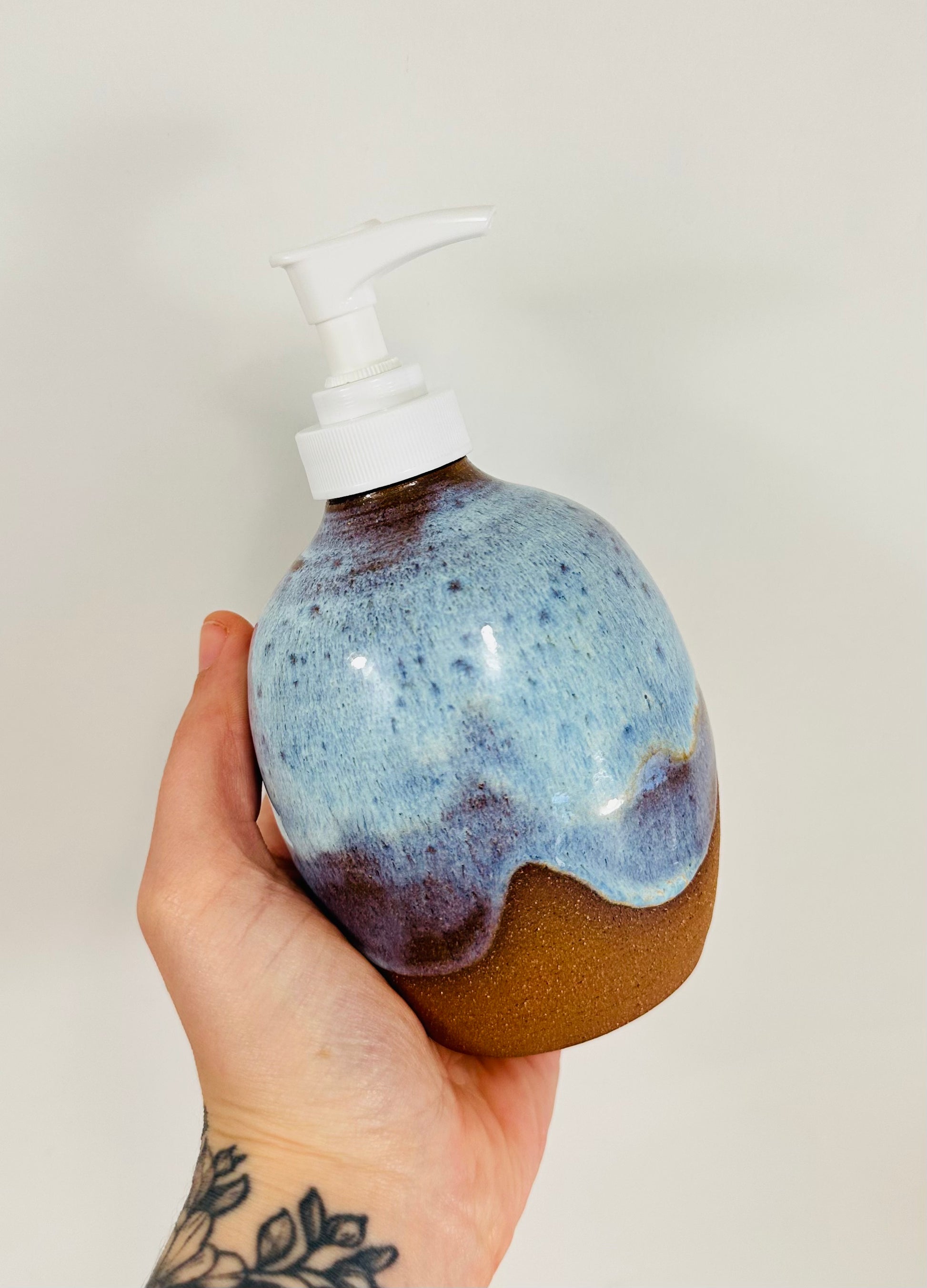 A handmade ceramic soap dispenser in red clay with a beautiful blue glaze.
