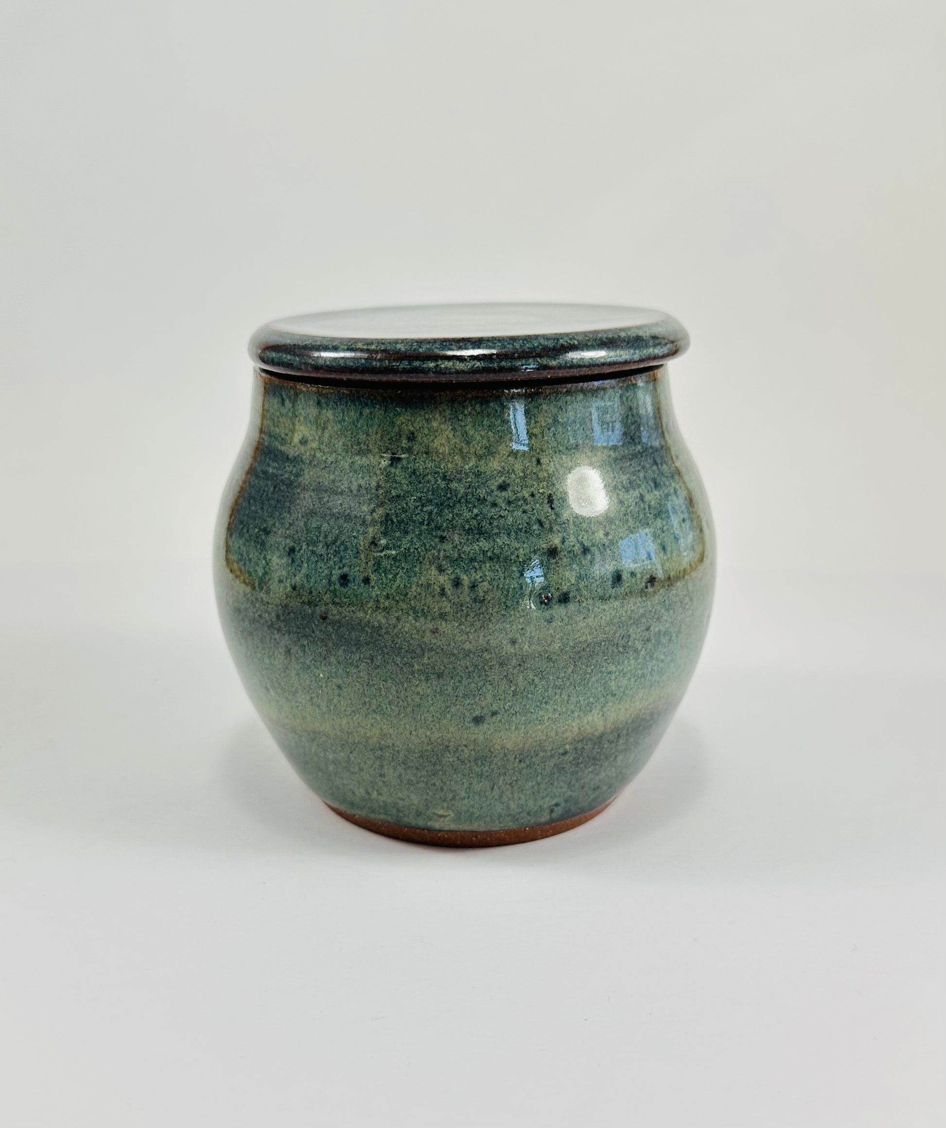 A handmade ceramic jar in red clay with a beautiful green glaze.
