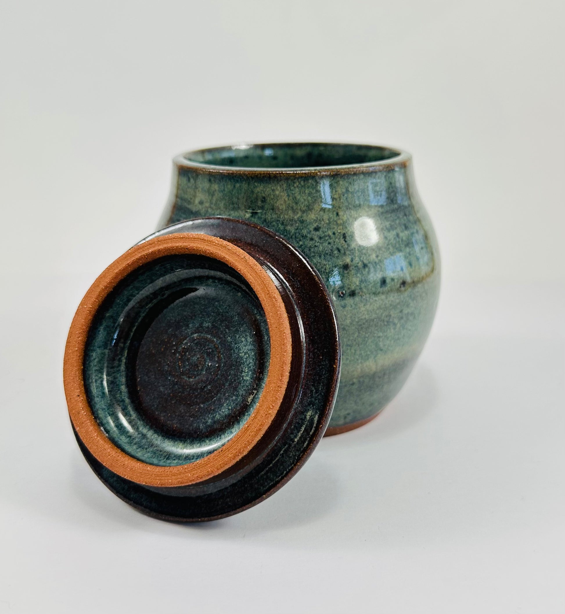 A handmade ceramic jar in red clay with a beautiful green glaze.
