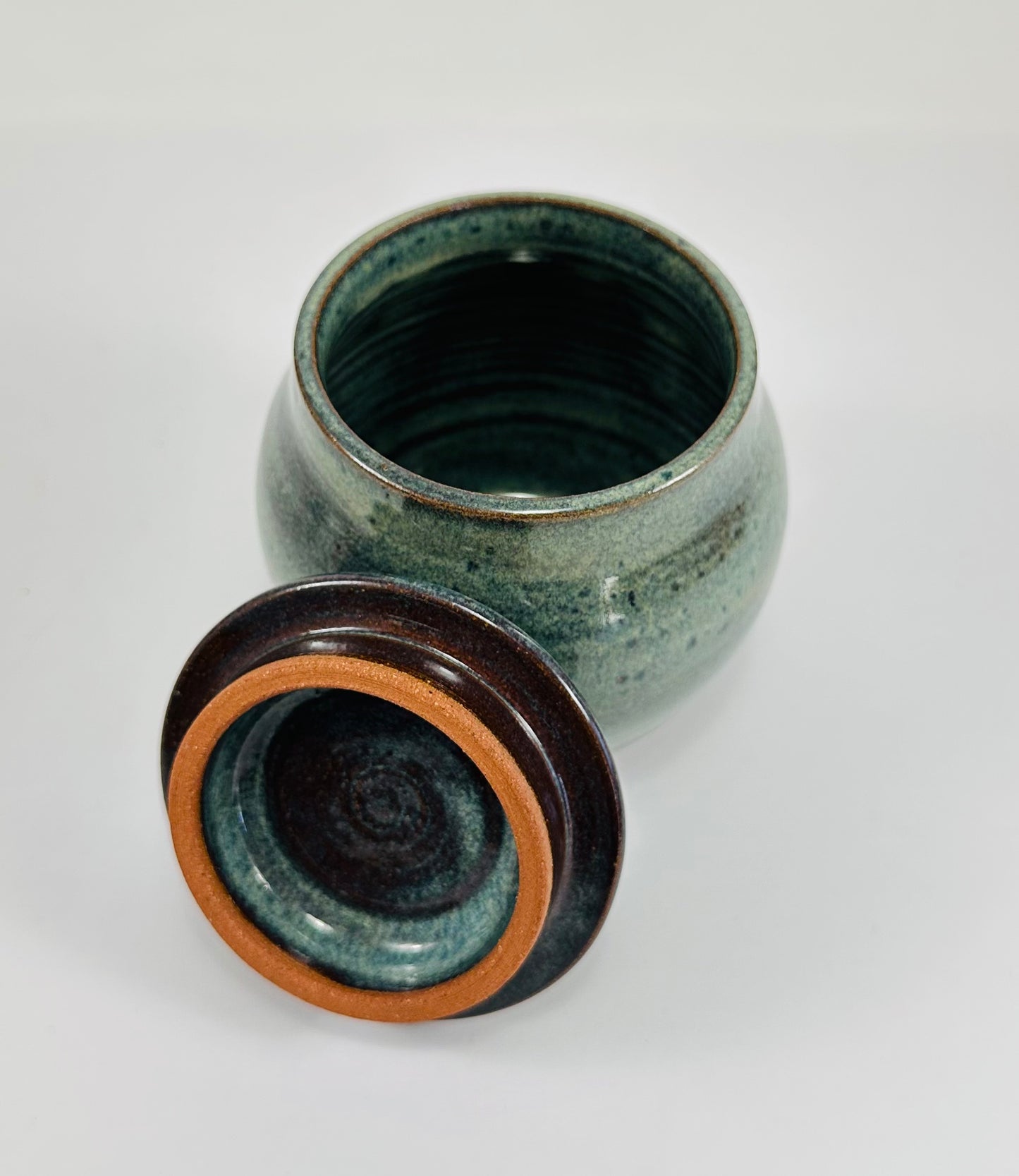 A handmade ceramic jar in red clay with a beautiful green glaze.