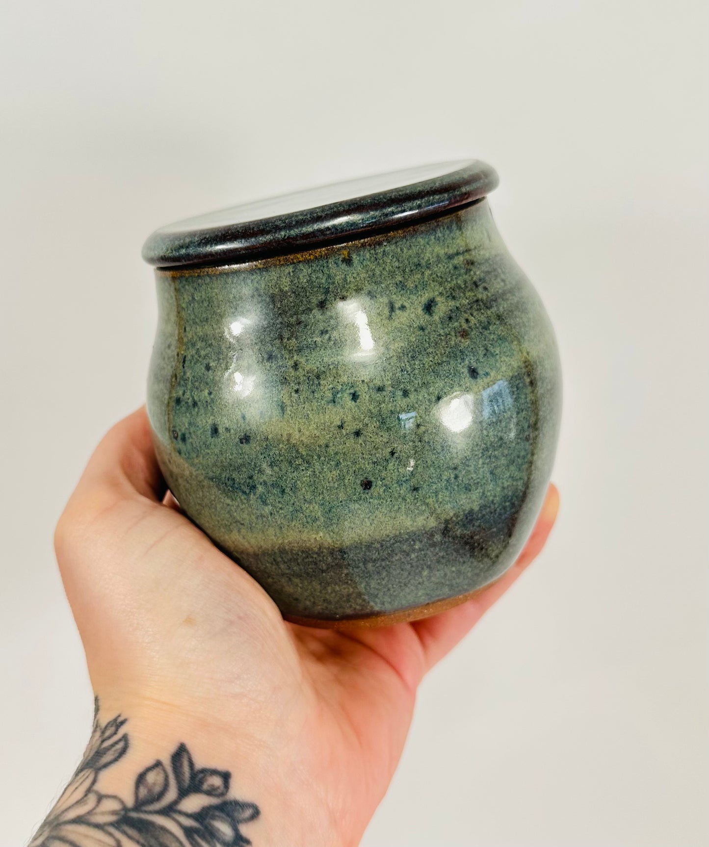 A handmade ceramic jar in red clay with a beautiful green glaze.