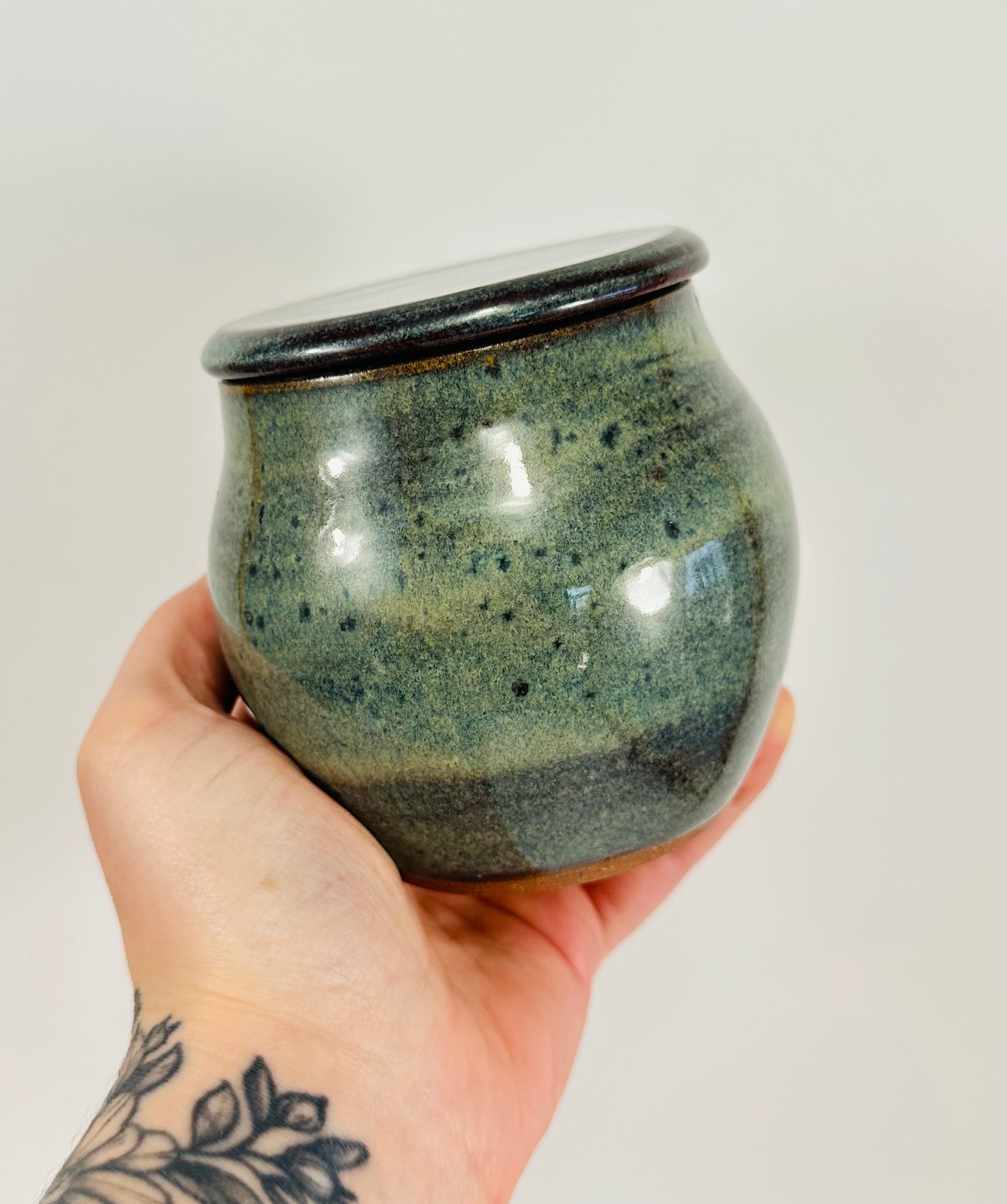 A handmade ceramic jar in red clay with a beautiful green glaze.