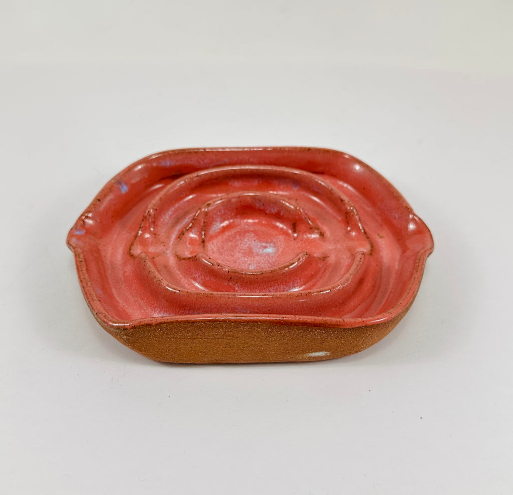 A handmade ceramic soap dish in a beautiful pink glaze. The dish is made from red clay.