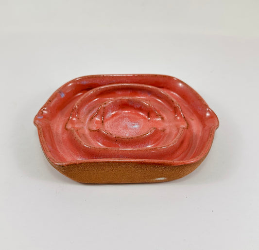 A handmade ceramic soap dish in a beautiful pink glaze. The dish is made from red clay.