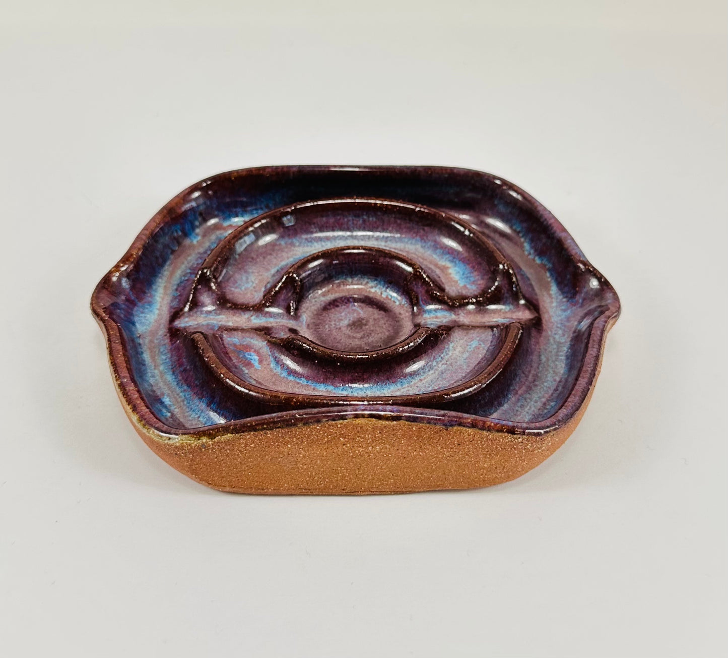 A handmade ceramic soap dish in a beautiful purple glaze. The dish is made from red clay.