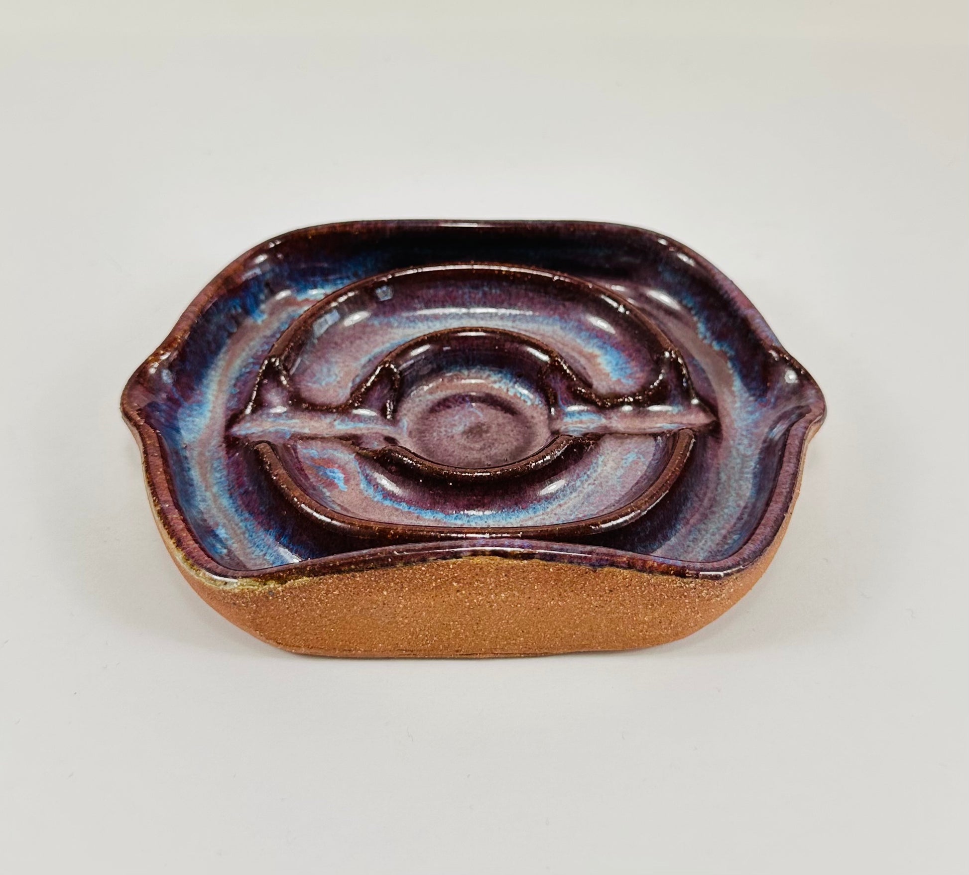 A handmade ceramic soap dish in a beautiful purple glaze. The dish is made from red clay.