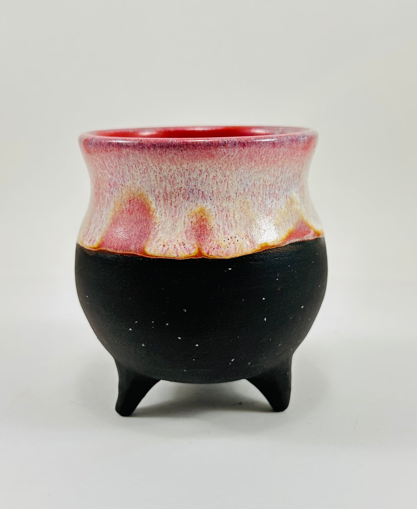 A handmade ceramic cauldron in pink and black glaze.