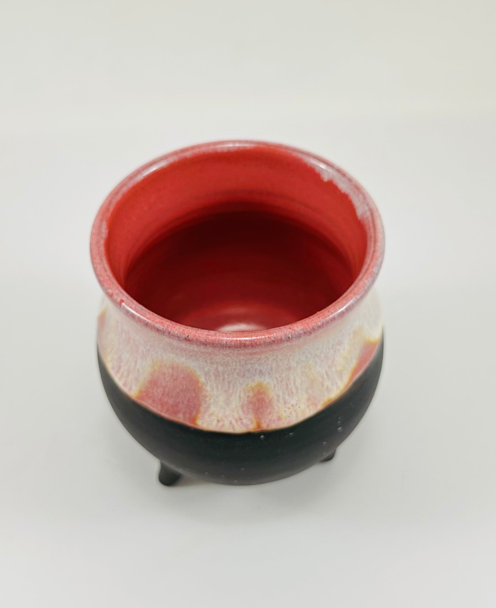 A handmade ceramic cauldron in pink and black glaze.