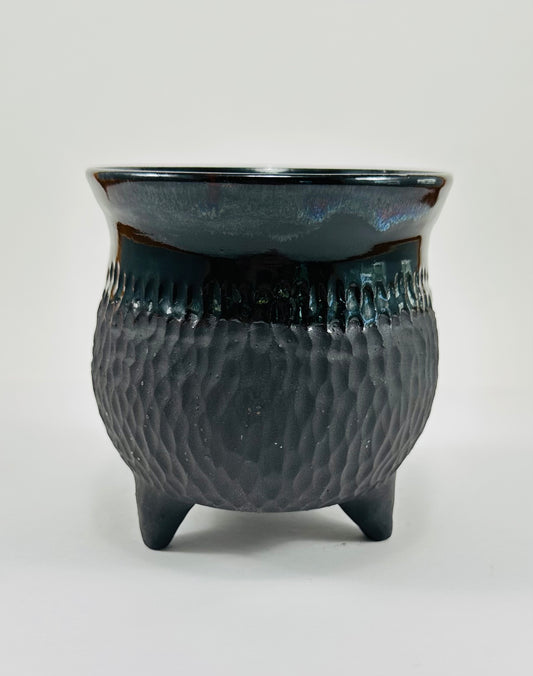 A handmade ceramic cauldron in a beautiful black glazes with hints of blue. 