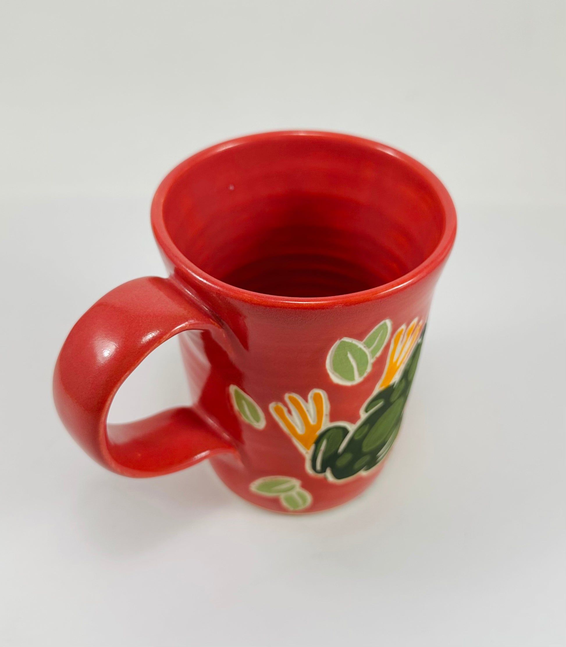 Pink mug with a green frog design on a white background