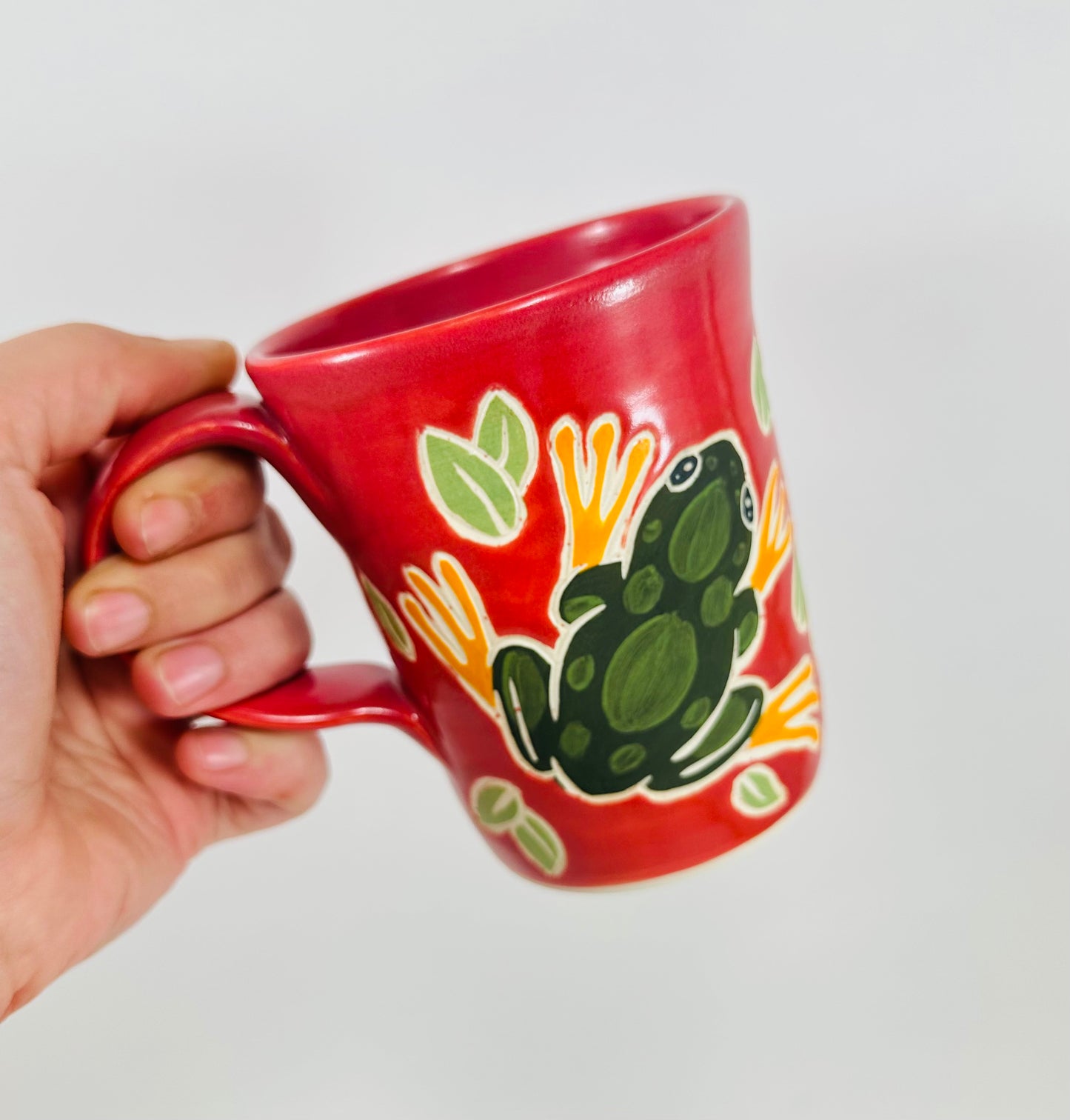 Pink mug with a green frog design on a white background