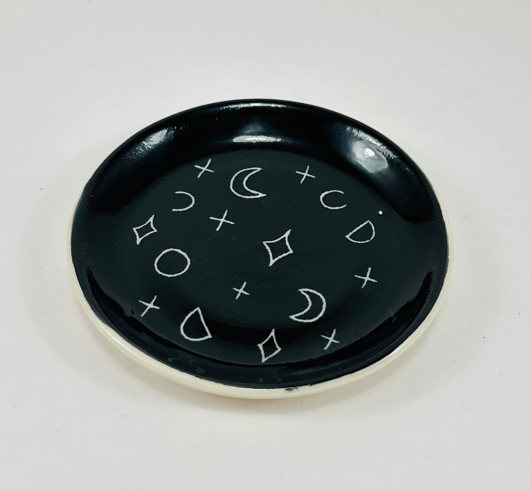 Handmade trinket dish in  black and white glaze with moons and stars.