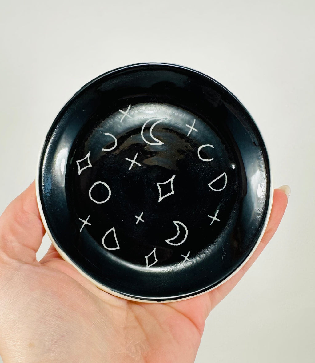 Handmade trinket dish in  black and white glaze with moons and stars.