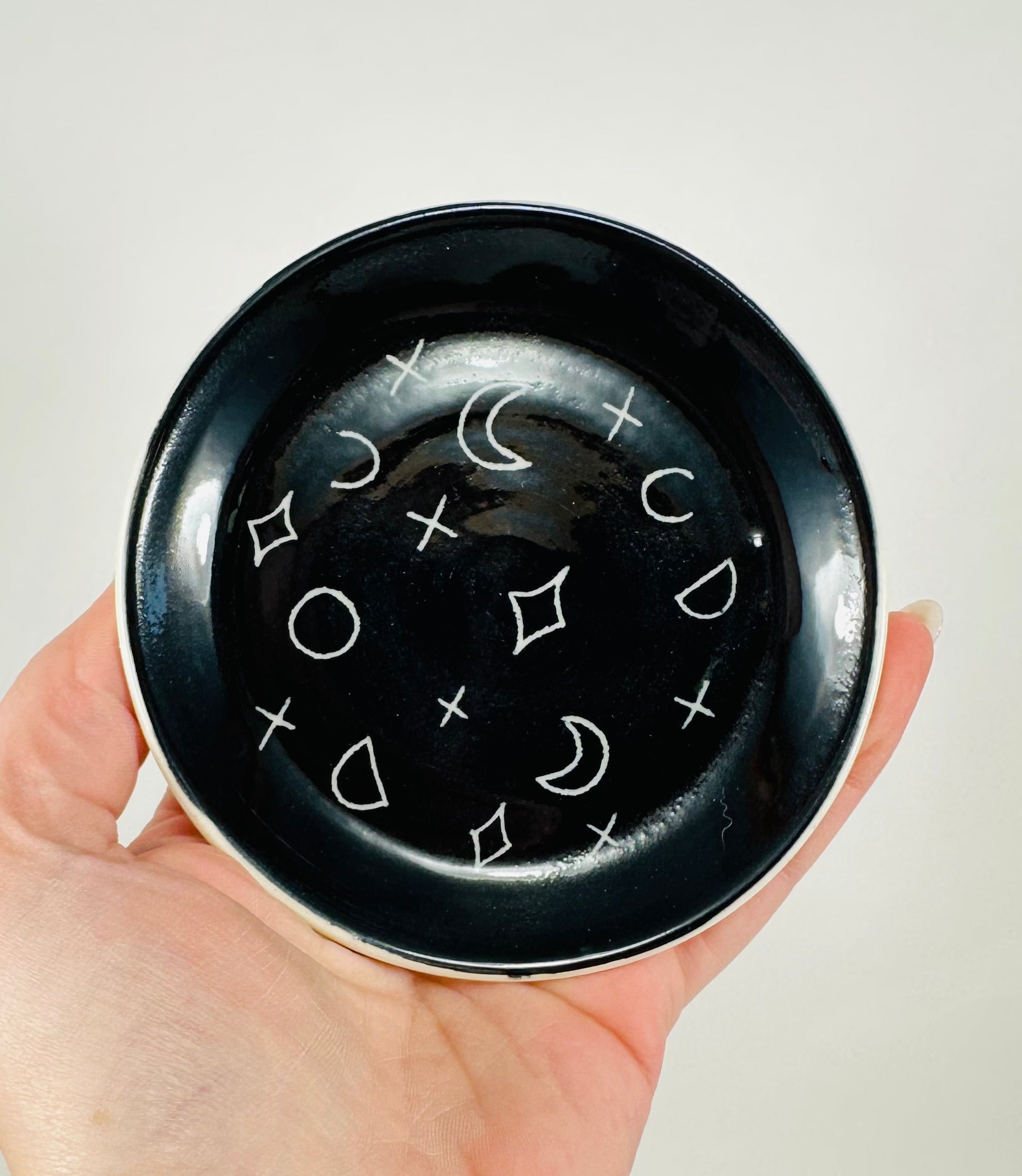 Handmade trinket dish in  black and white glaze with moons and stars.