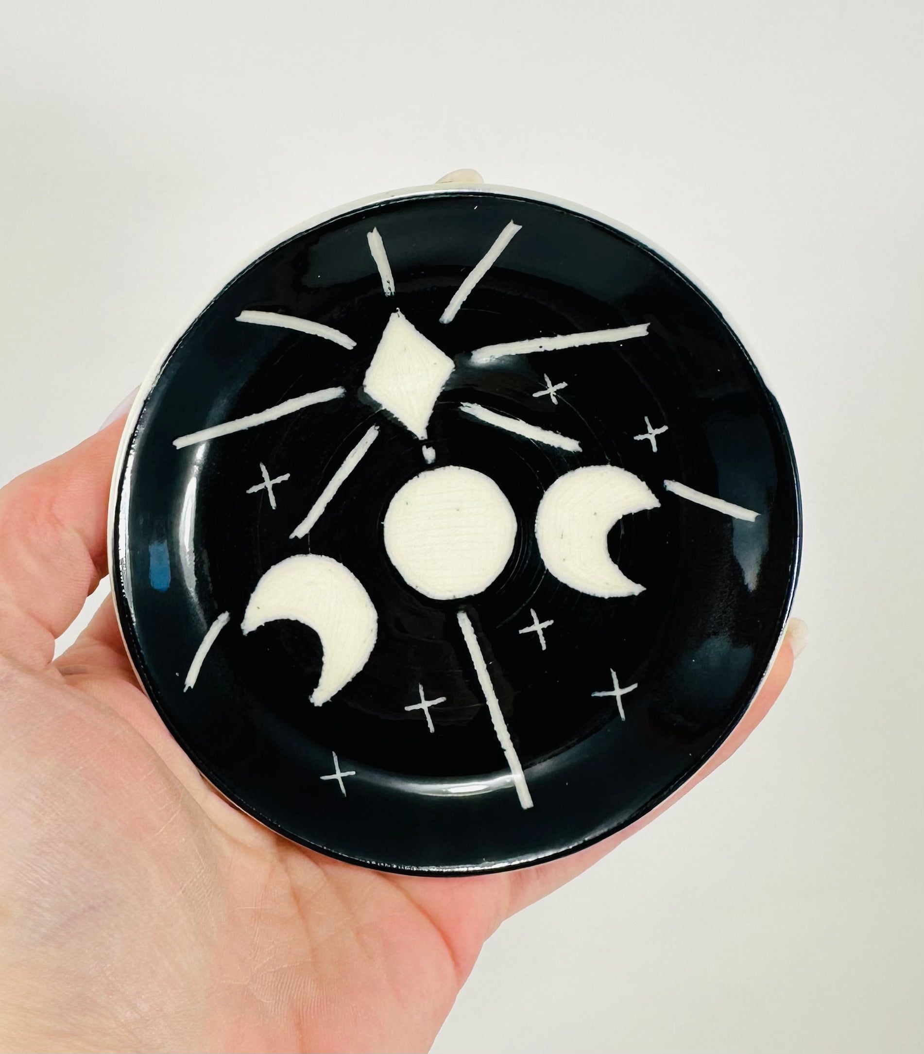 Handmade trinket dish in  black and white glaze with moons and stars.