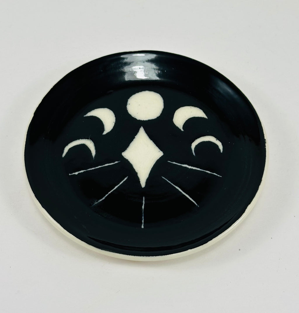 Handmade trinket dish in black and white glaze with moons and stars.