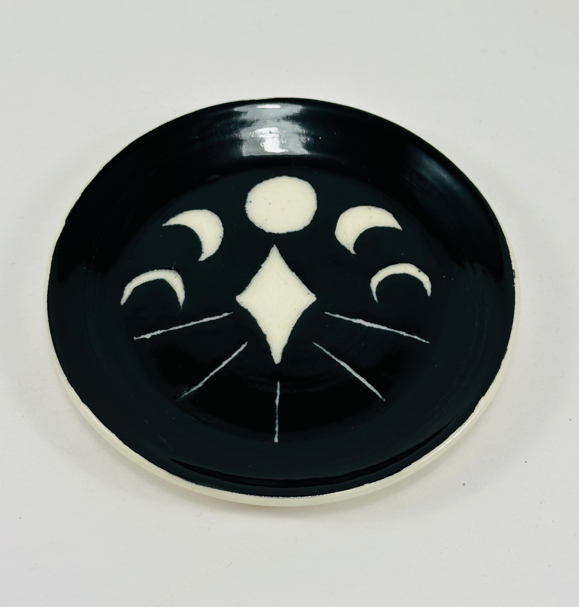 Handmade trinket dish in black and white glaze with moons and stars.