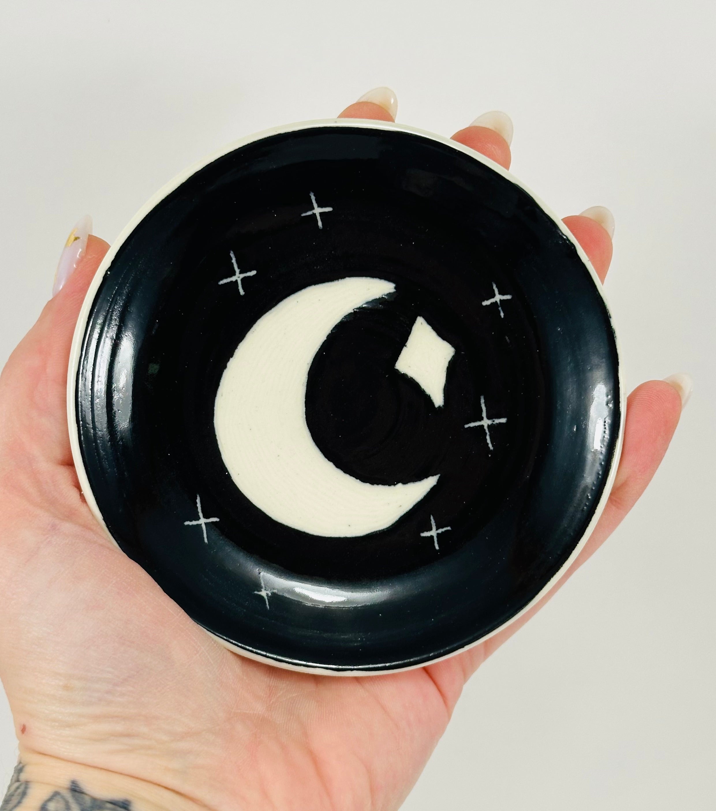 Handmade trinket dish in black and white glaze with moons and stars.