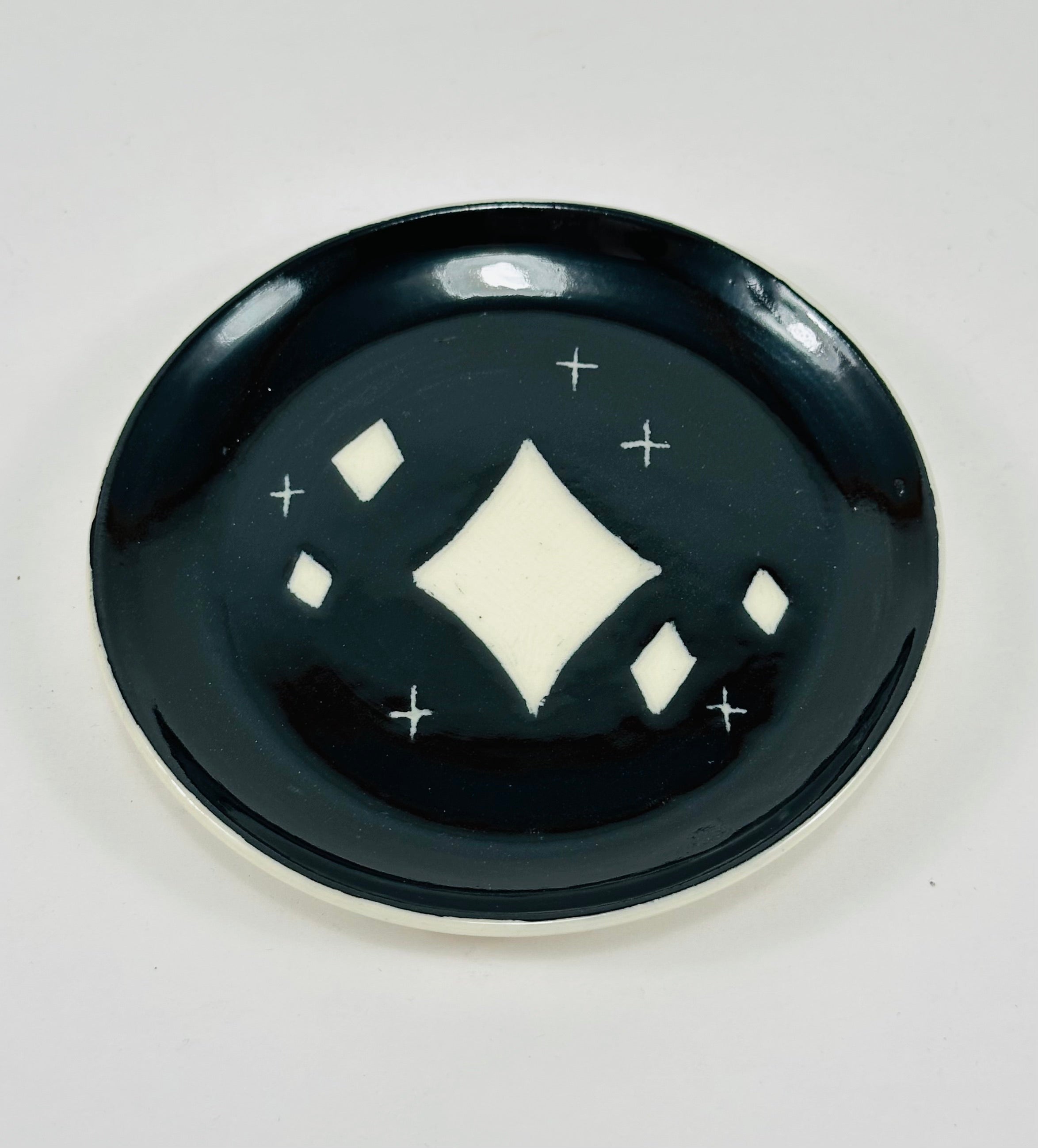 Handmade trinket dish in black and white glaze with stars.