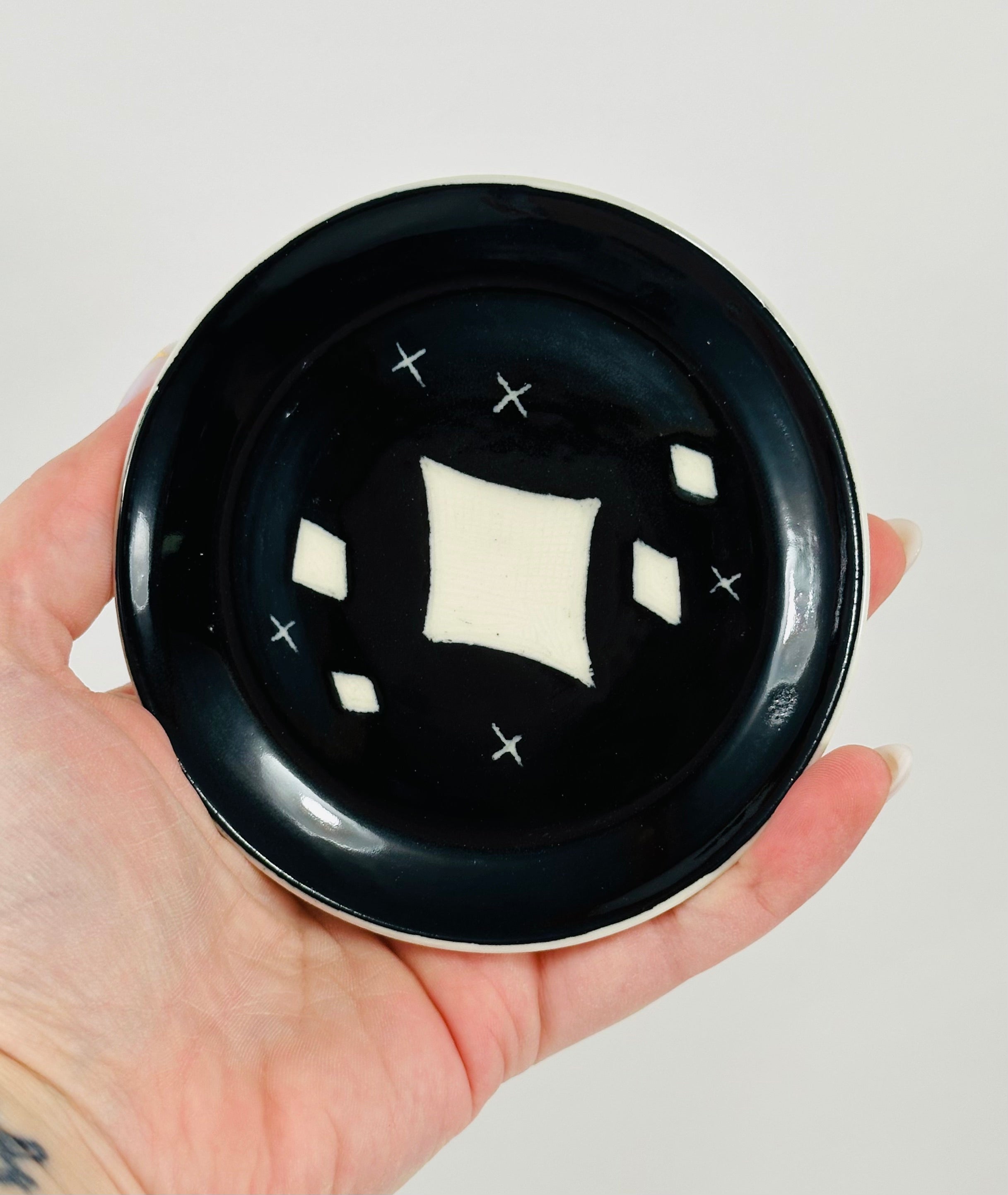 Handmade trinket dish in black and white glaze with stars.