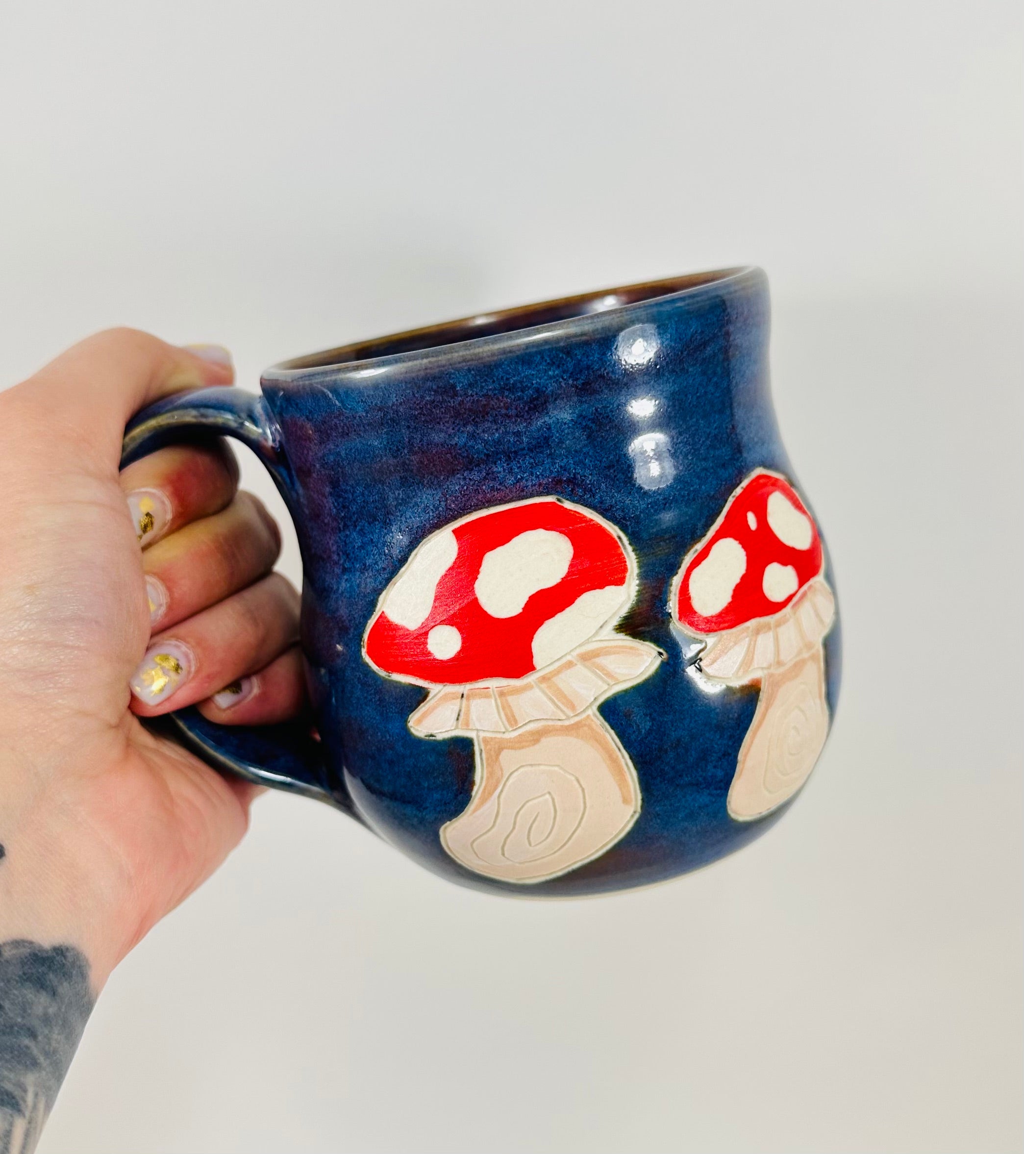 Handmade ceramic mug with mushroom illustrations on it and a beautiful blue glaze.