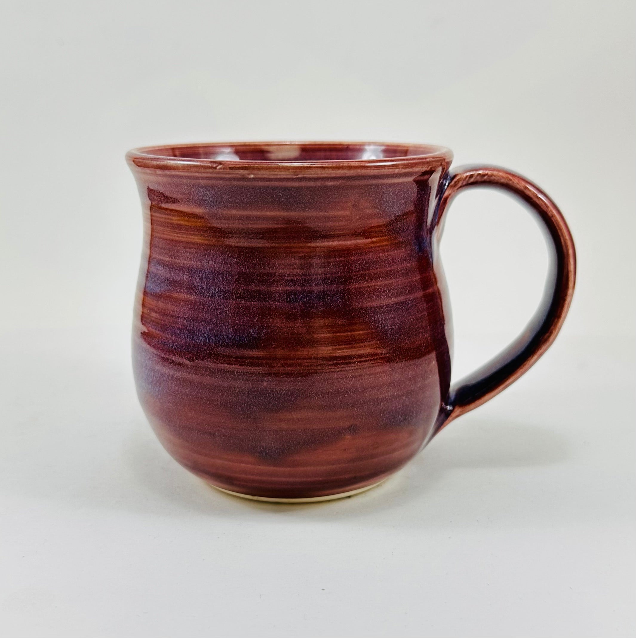 handmade ceramic mug in a beautiful purple glaze and a skull illustration on it.