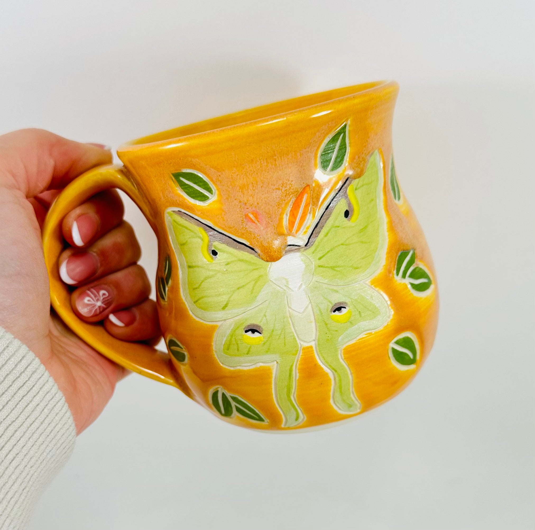 handmade ceramic mug in a beautiful yellow glaze and a luna moth illustration on it.