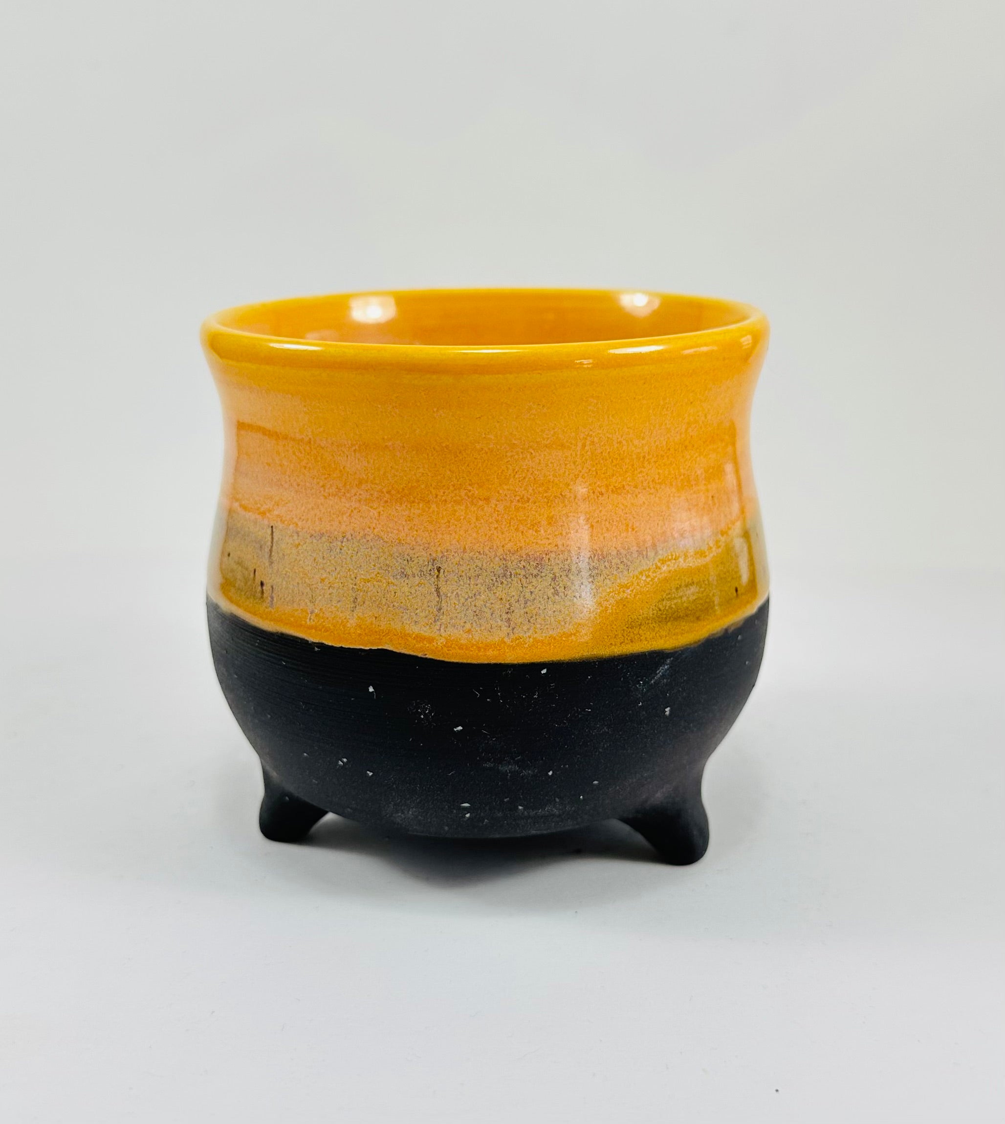 A handmade ceramic cauldron in a beautiful yellow and black glaze
